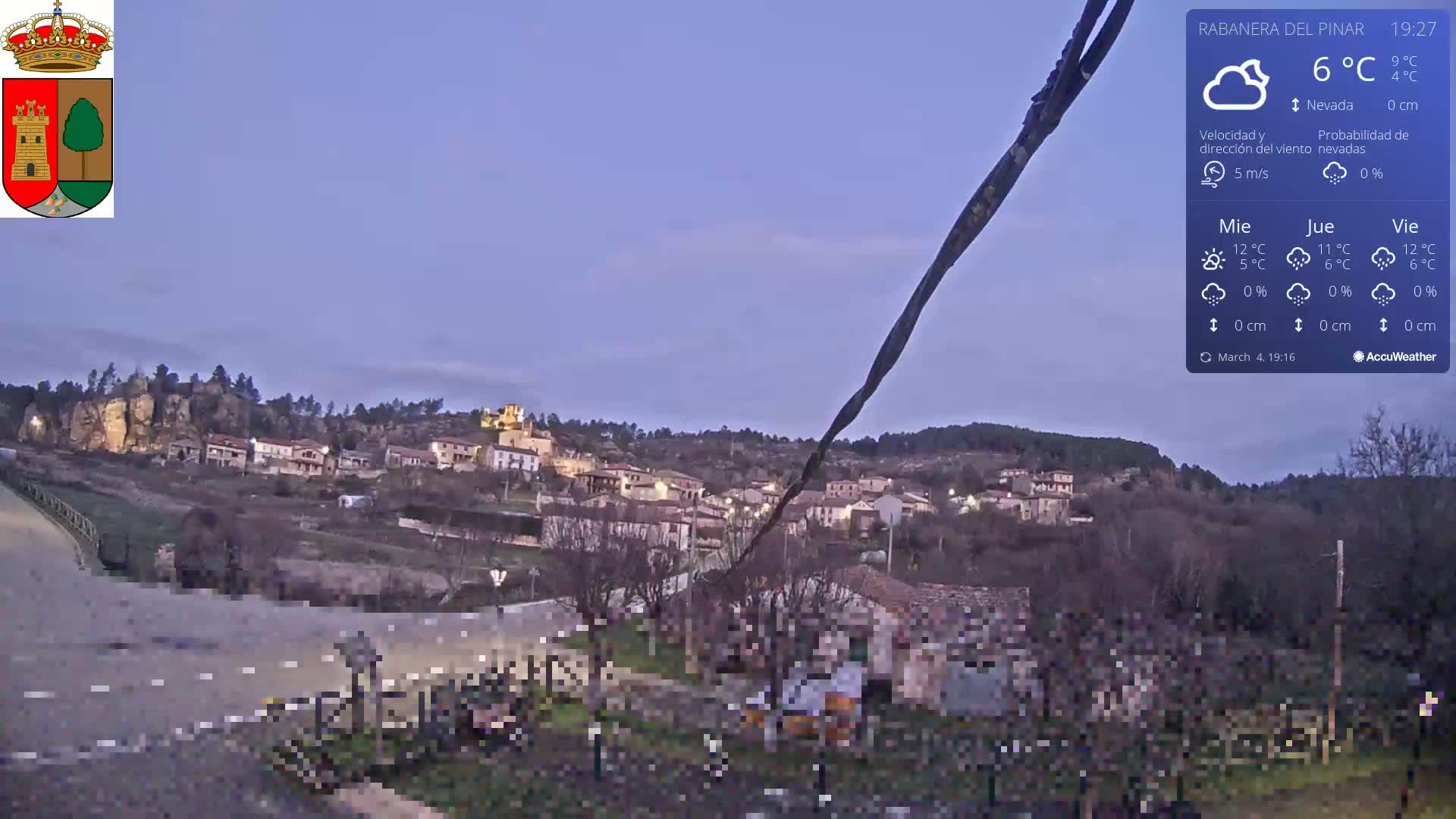 A small village nestled on a hillside is seen at dusk under a mostly clear, twilight sky.