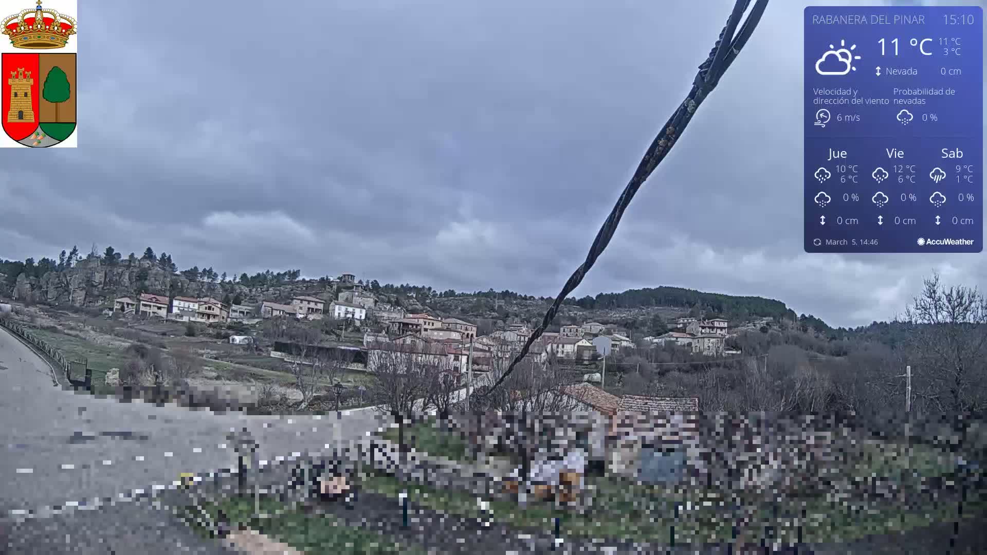 A small village nestled in a hilly landscape under a cloudy, overcast sky.