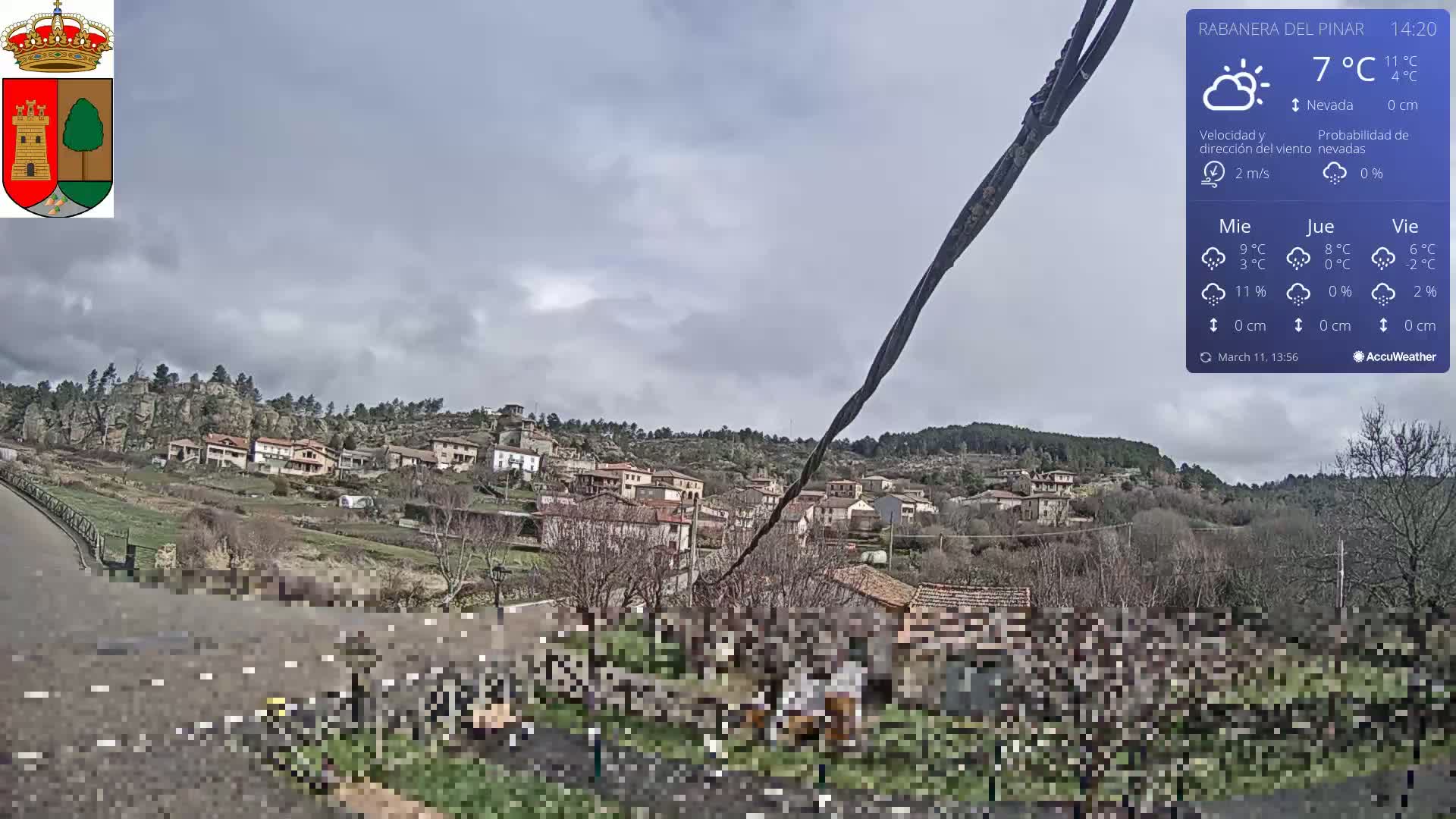 A small village nestled in a hilly landscape under a cloudy sky.