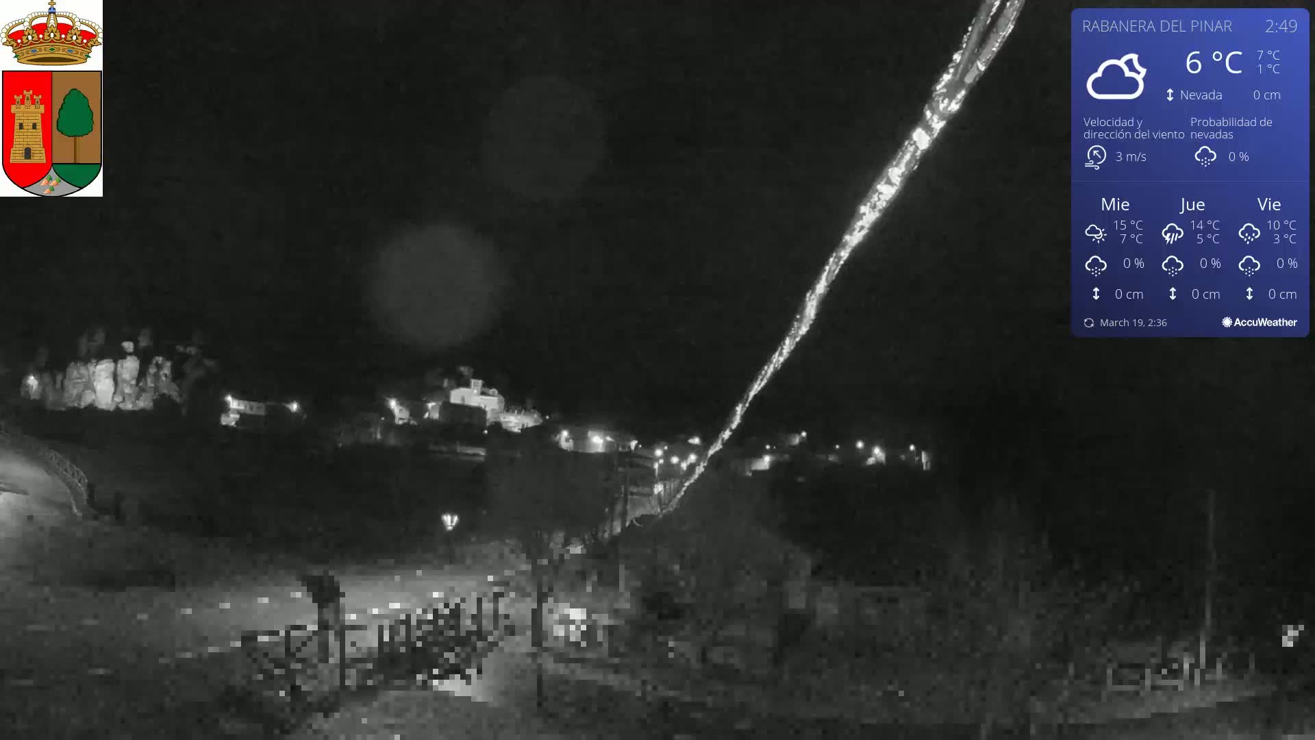 A nighttime view of a small town under a dark sky with light snow falling and a bright streak in the sky.