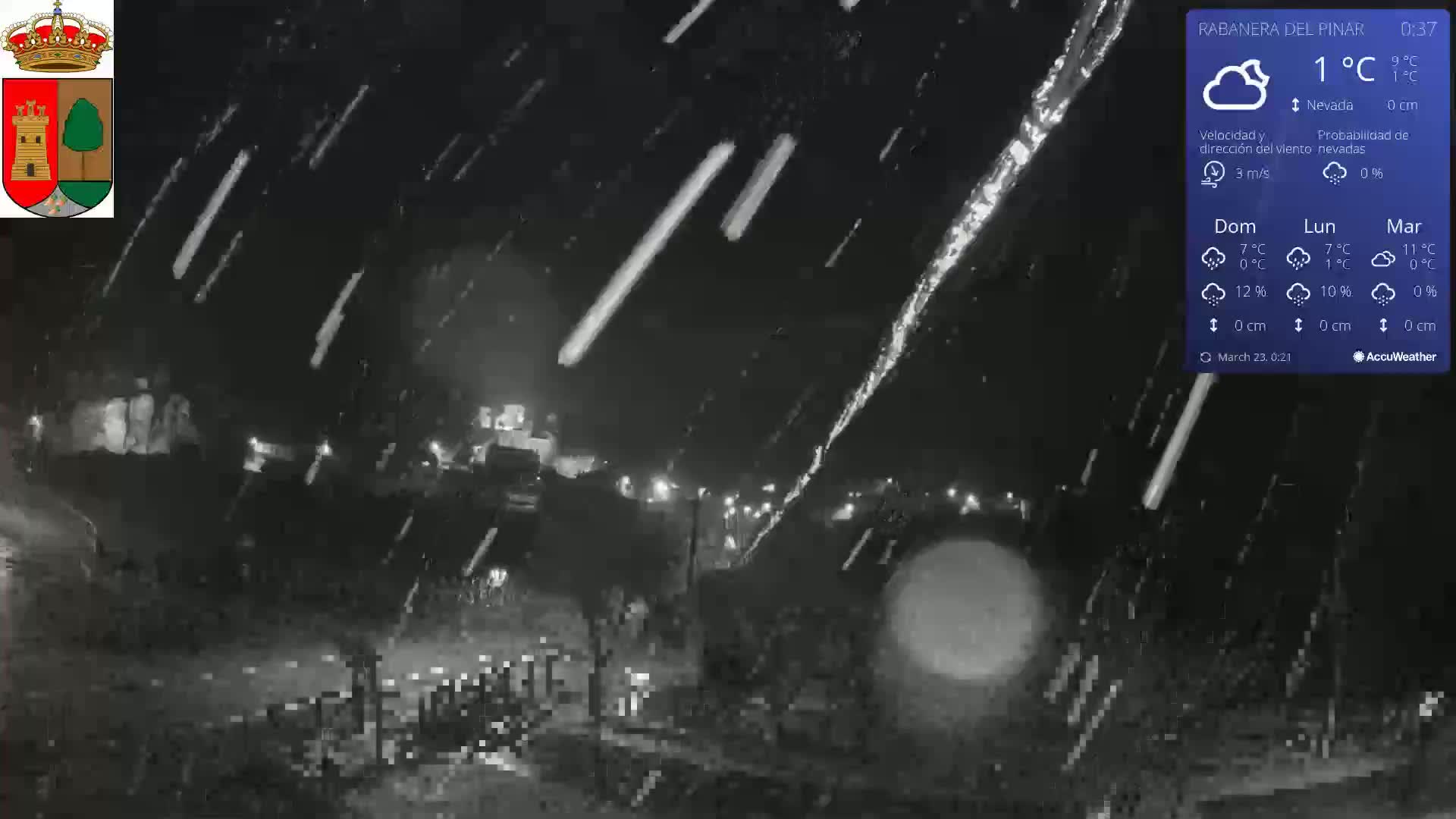 A nighttime scene of rain falling, illuminated by faint streetlights, with a visible icicle.