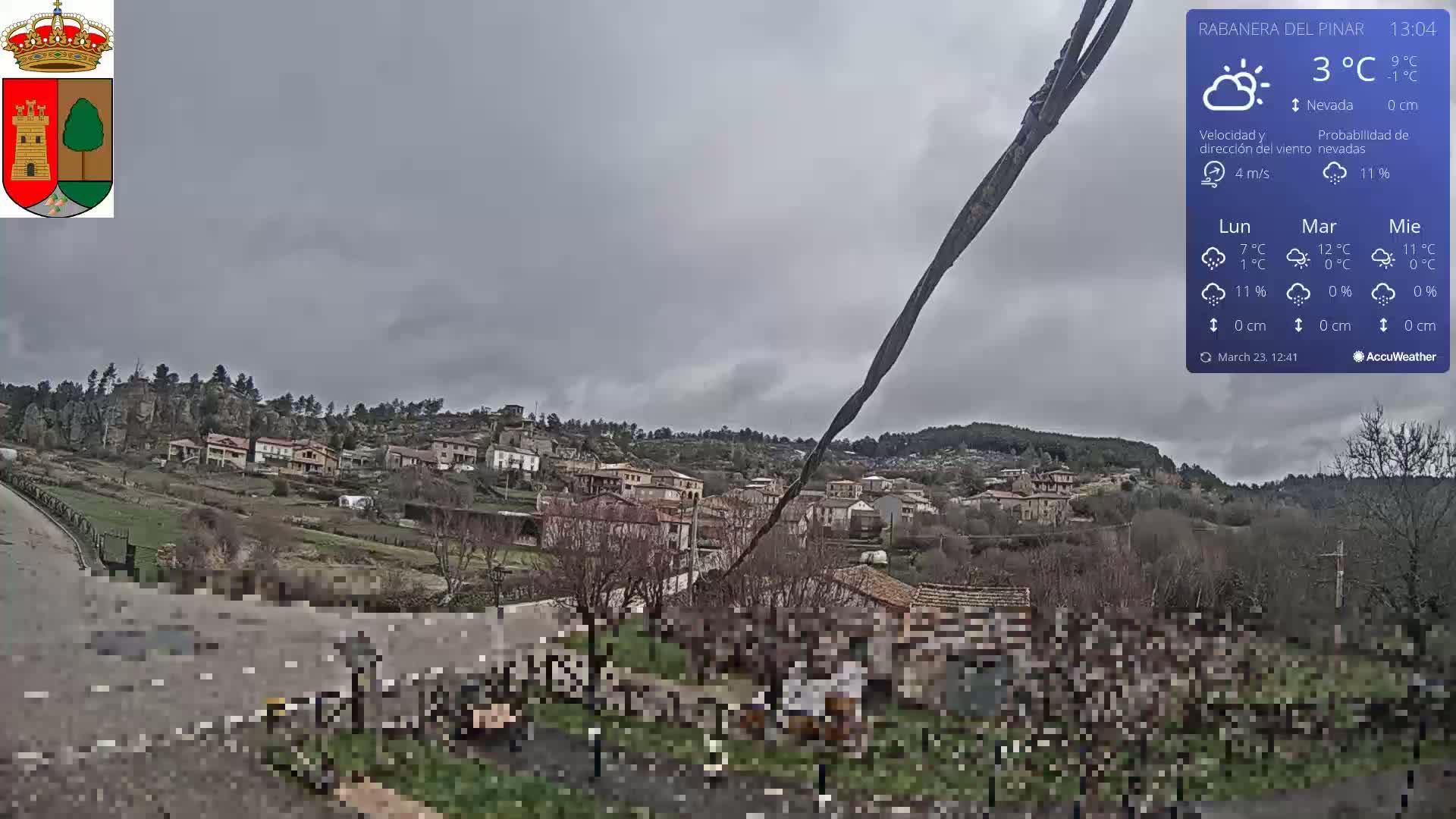 A small village nestled in a hilly landscape under an overcast sky.