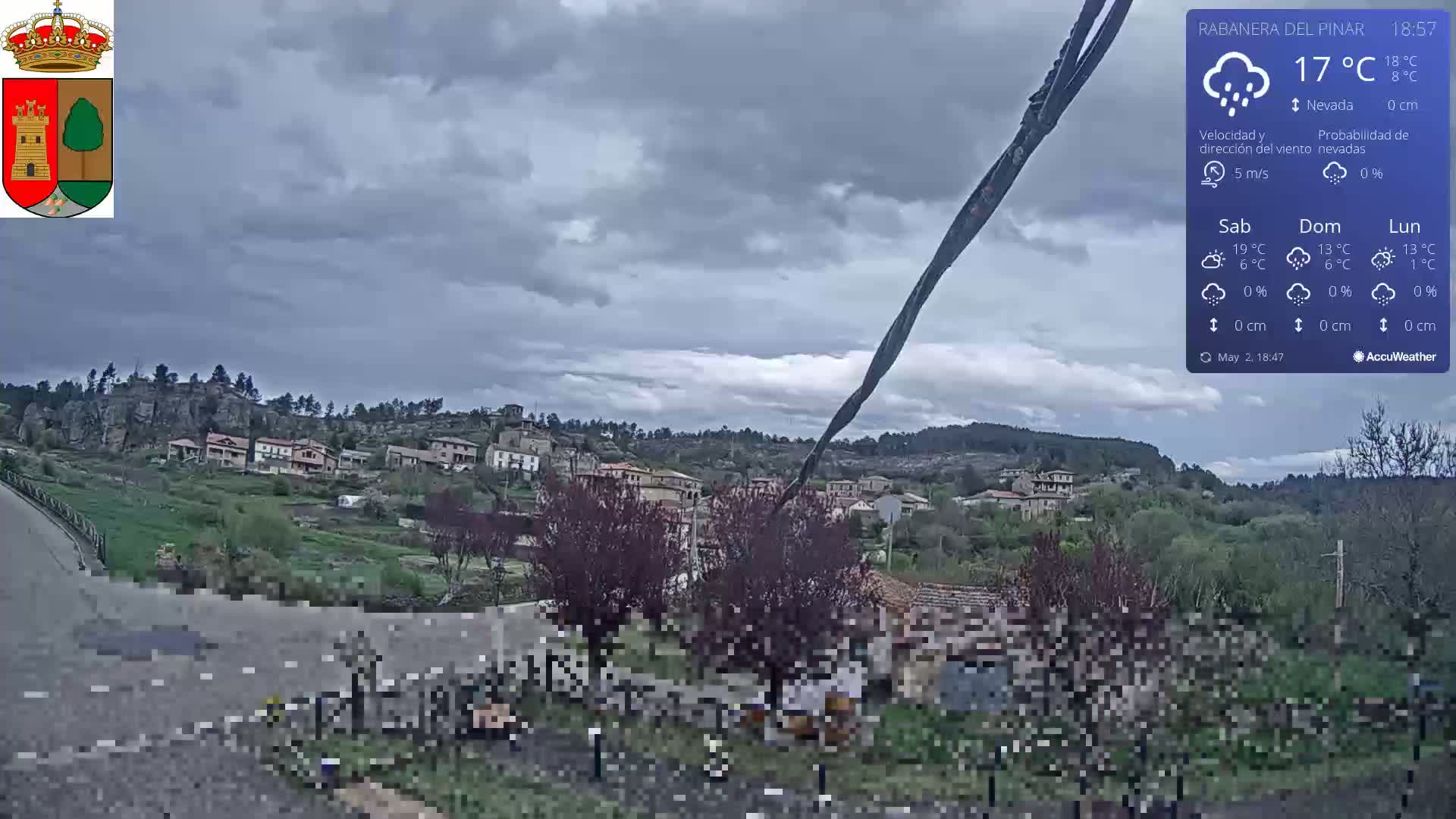 A small village nestled in a hilly landscape under a cloudy, overcast sky.
