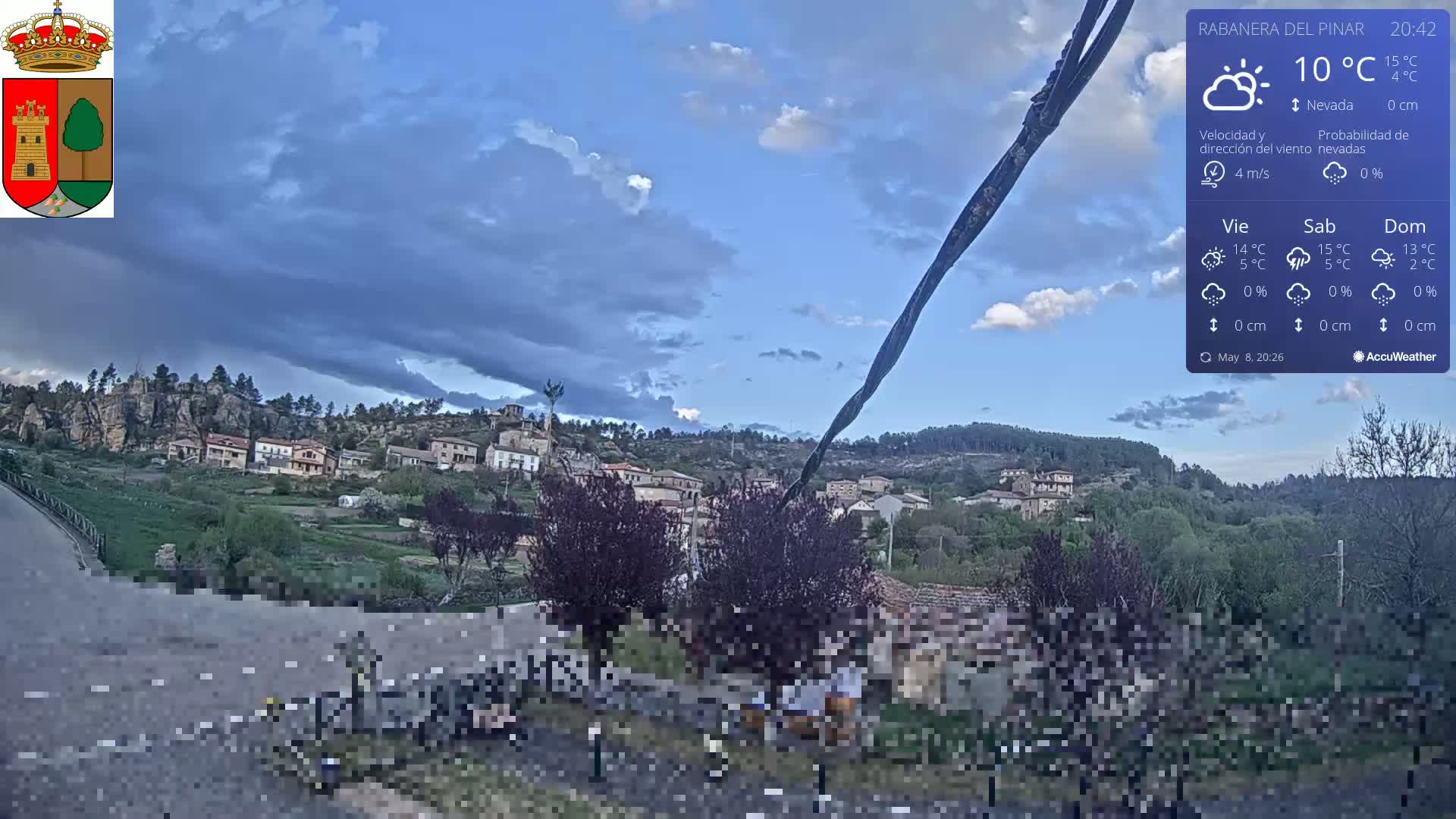 A small village nestled in a hilly landscape under a partly cloudy sky.