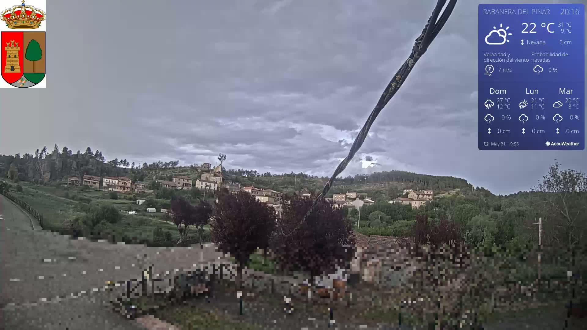 A small village nestled on a hillside under a mostly cloudy sky.