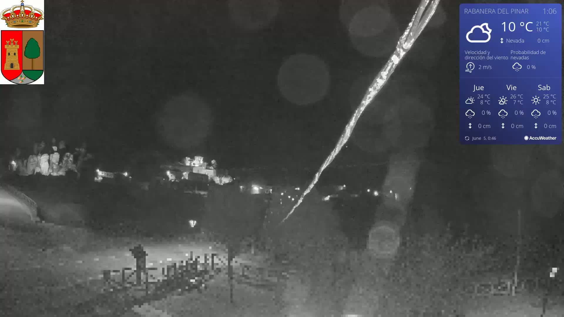 A nighttime, snowy scene shows a dimly lit town with a bright streak in the sky.