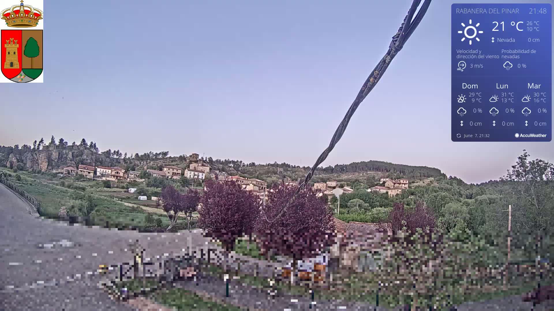 A small village nestled in a hilly landscape under a clear, twilight sky.