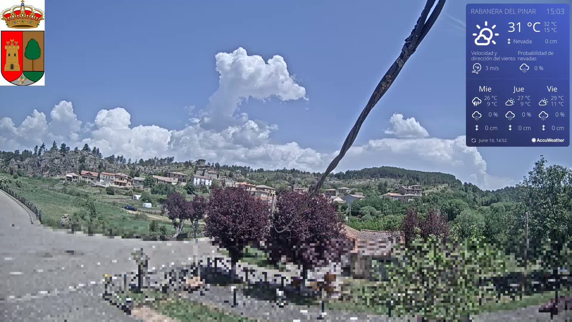 A partly cloudy day reveals a small village nestled in a green hillside, with a road in the foreground.