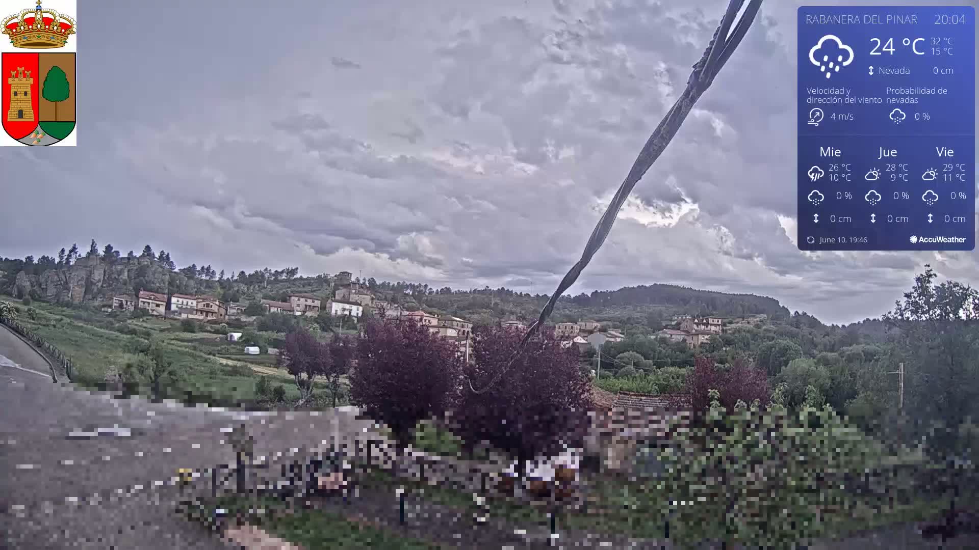 A small village nestled in a verdant valley under a cloudy, possibly stormy sky.