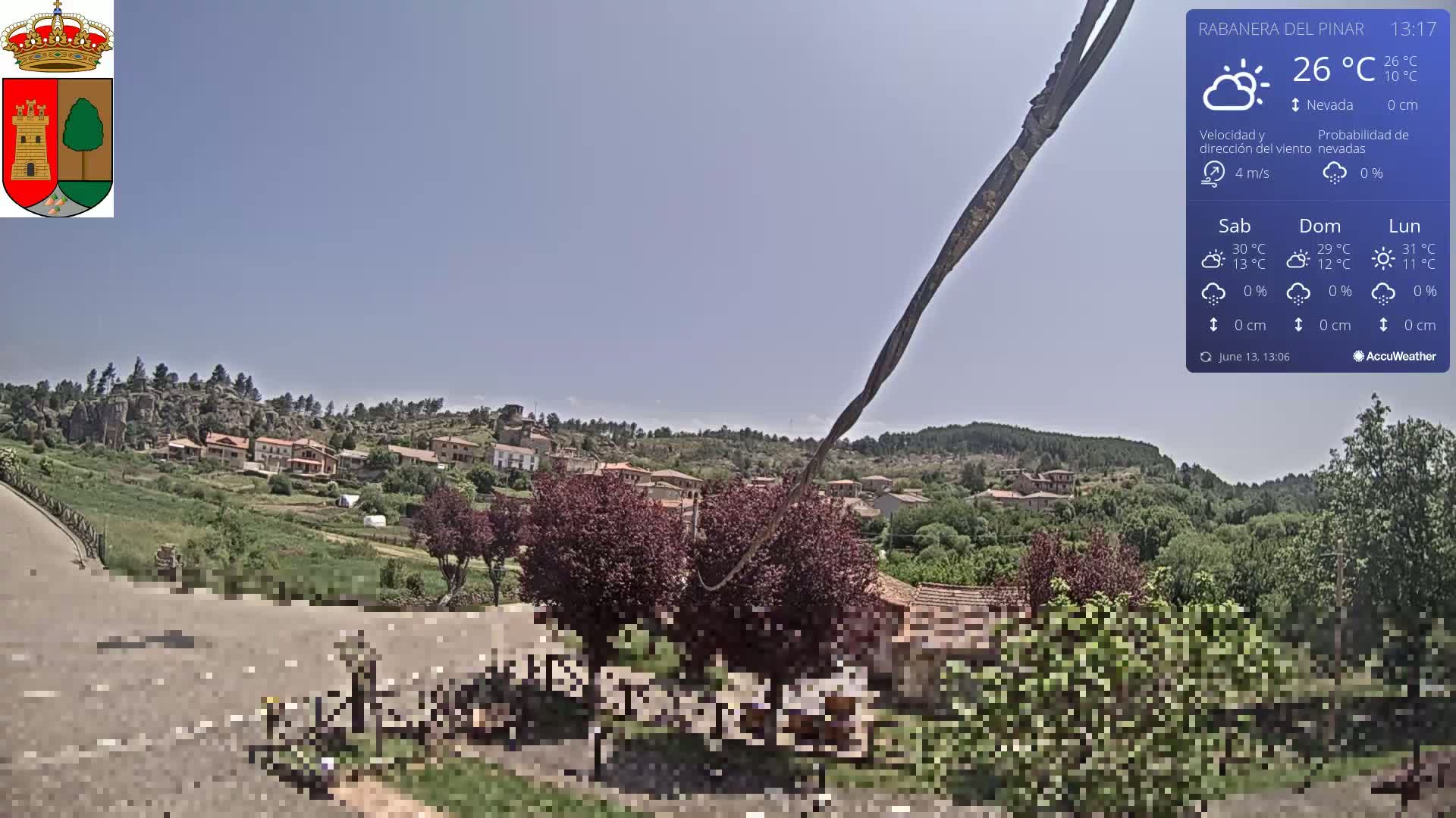 A sunny view of a small village nestled in a hilly, green landscape.
