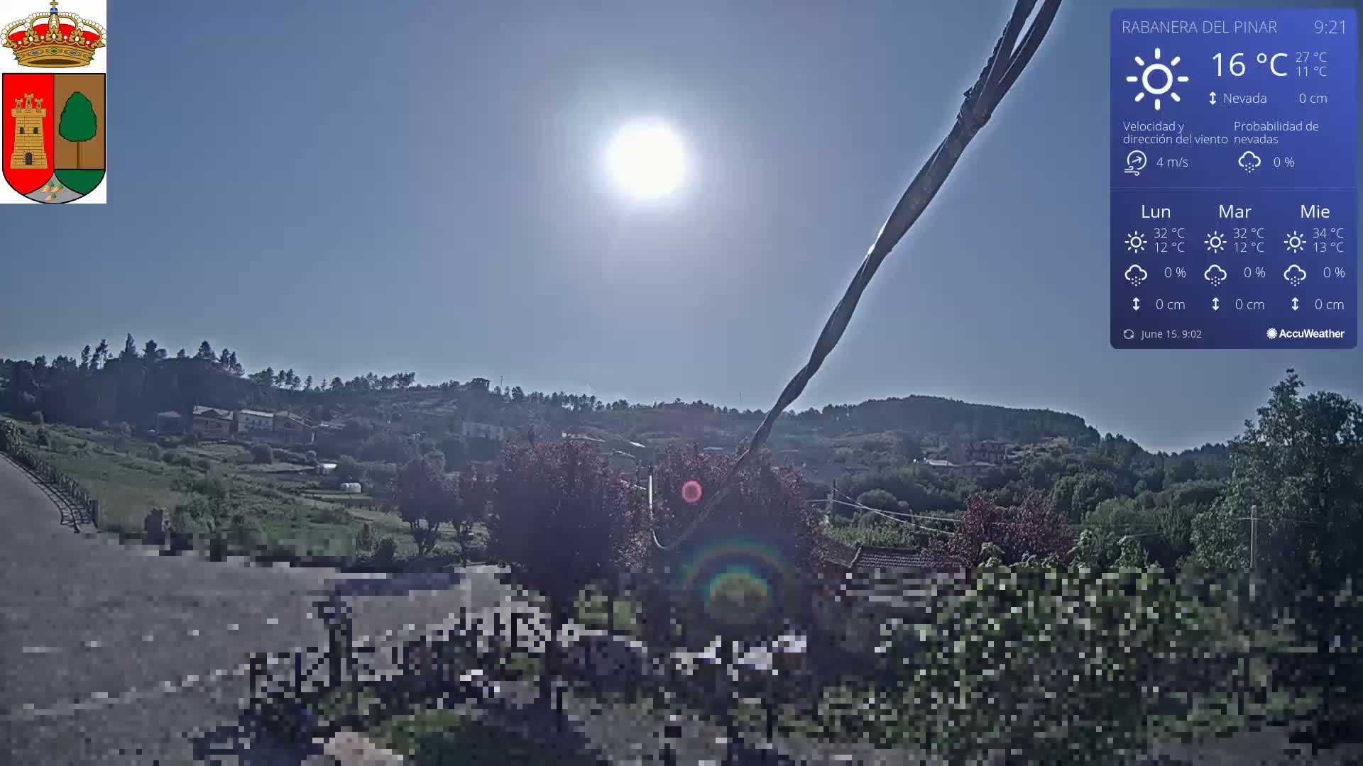 A sunny, clear day overlooking a small village nestled in a green hillside.