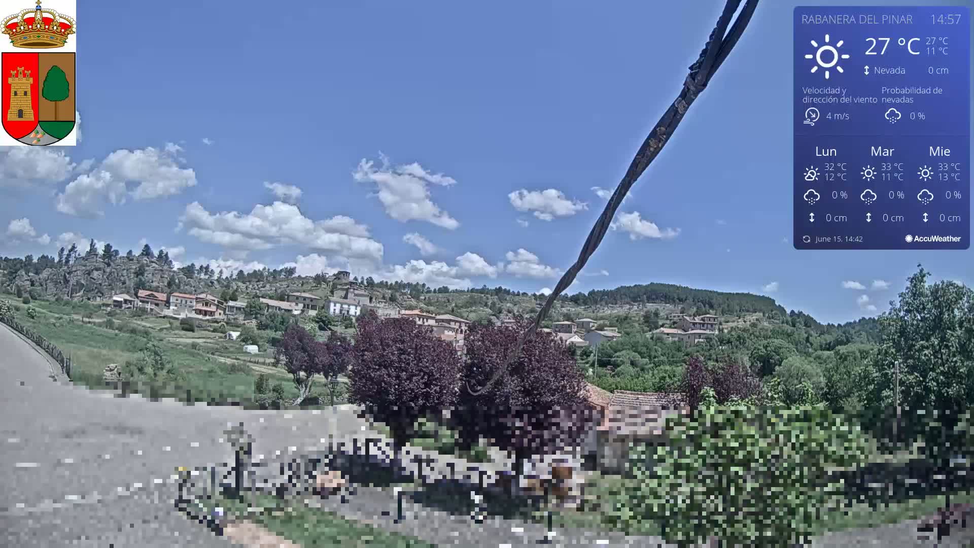 A partly cloudy day reveals a small village nestled in a verdant hillside, with a few dark-colored trees and rocky outcrops visible in the distance.