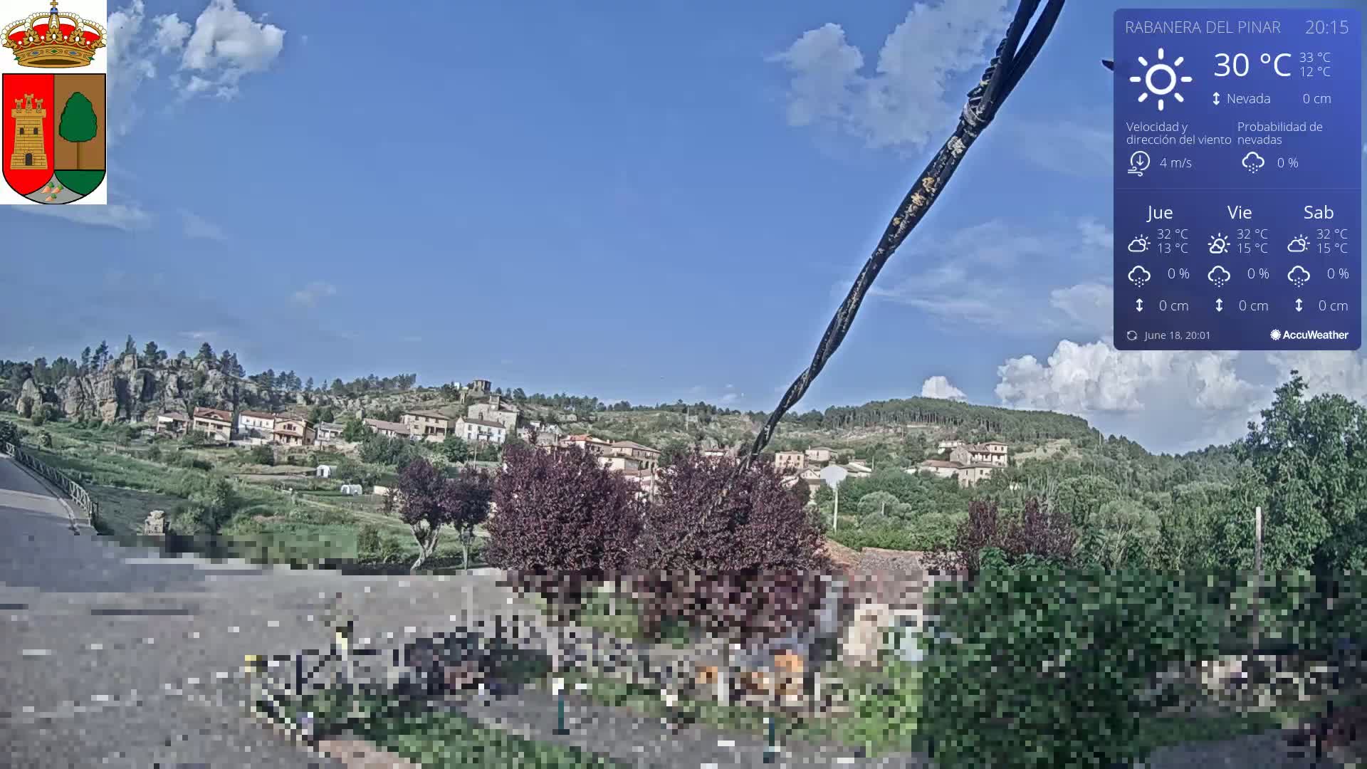 A small village nestled in a hilly landscape under a partly cloudy sky.