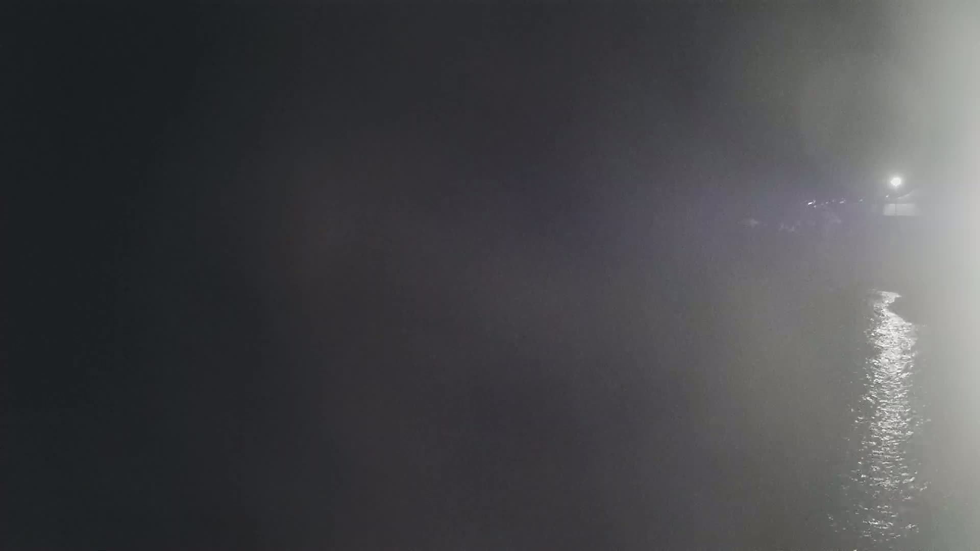 A dimly lit body of water is visible at night, obscured by fog or mist.