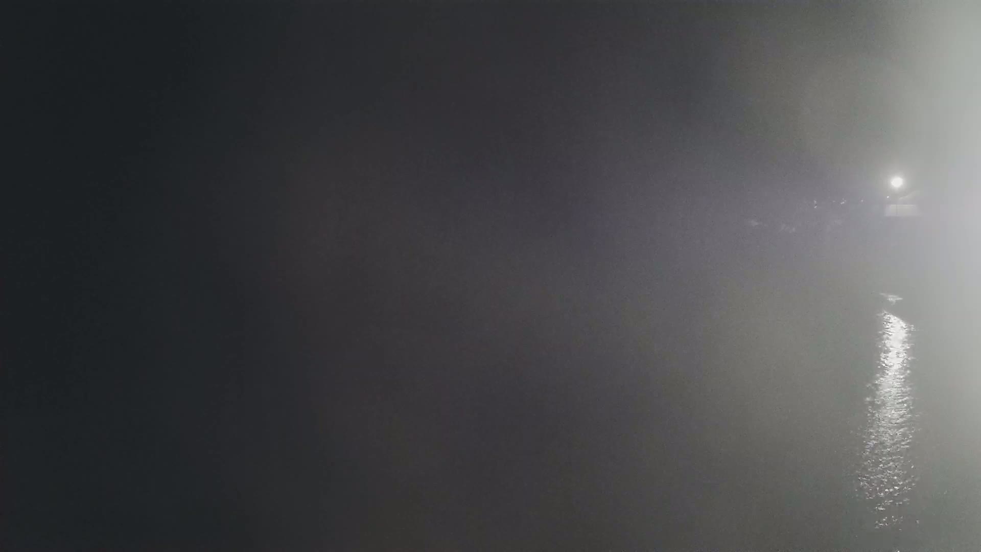 A body of water reflecting light at night in a foggy atmosphere.