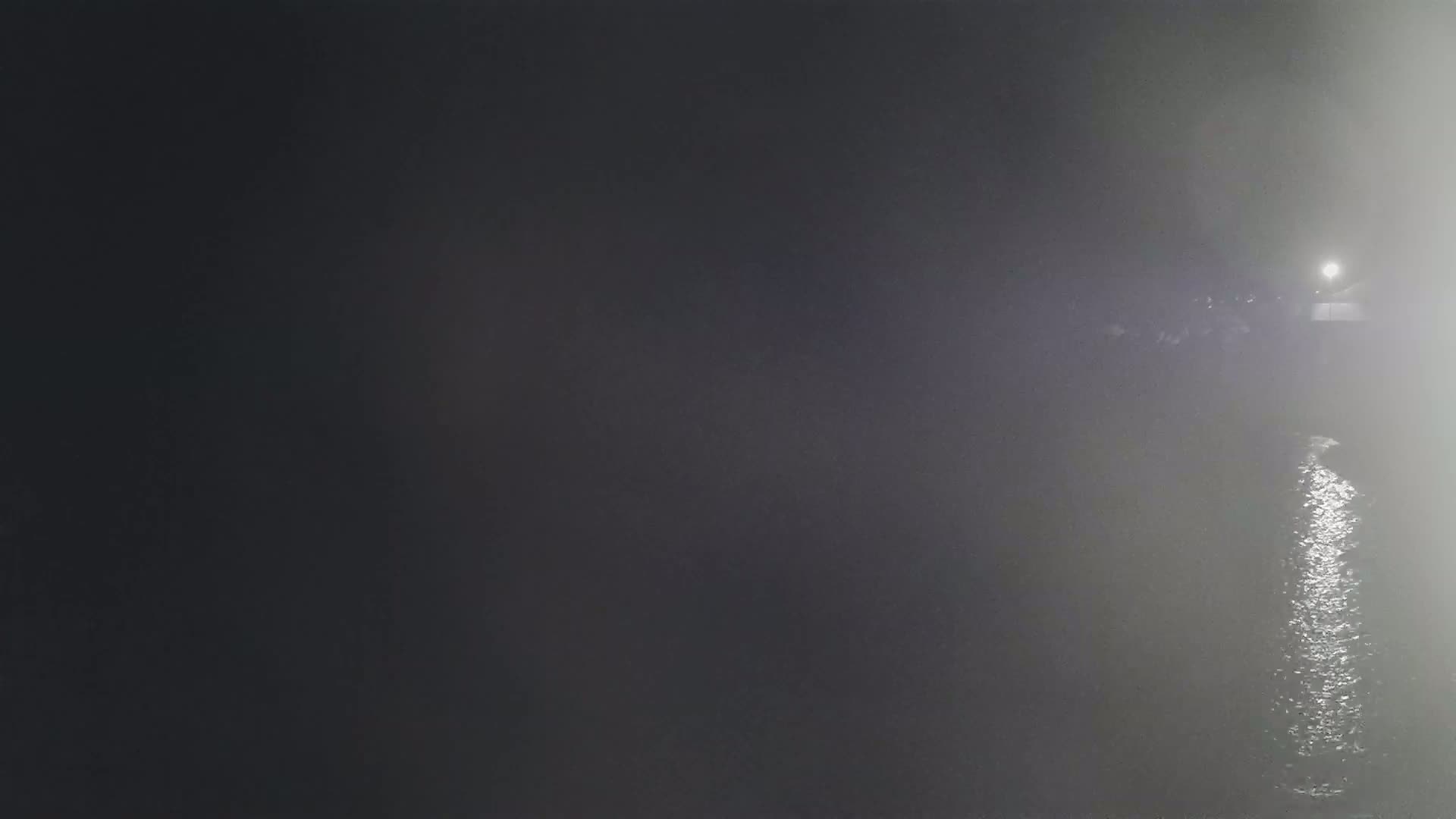 A dimly lit body of water is visible at night, shrouded in fog.