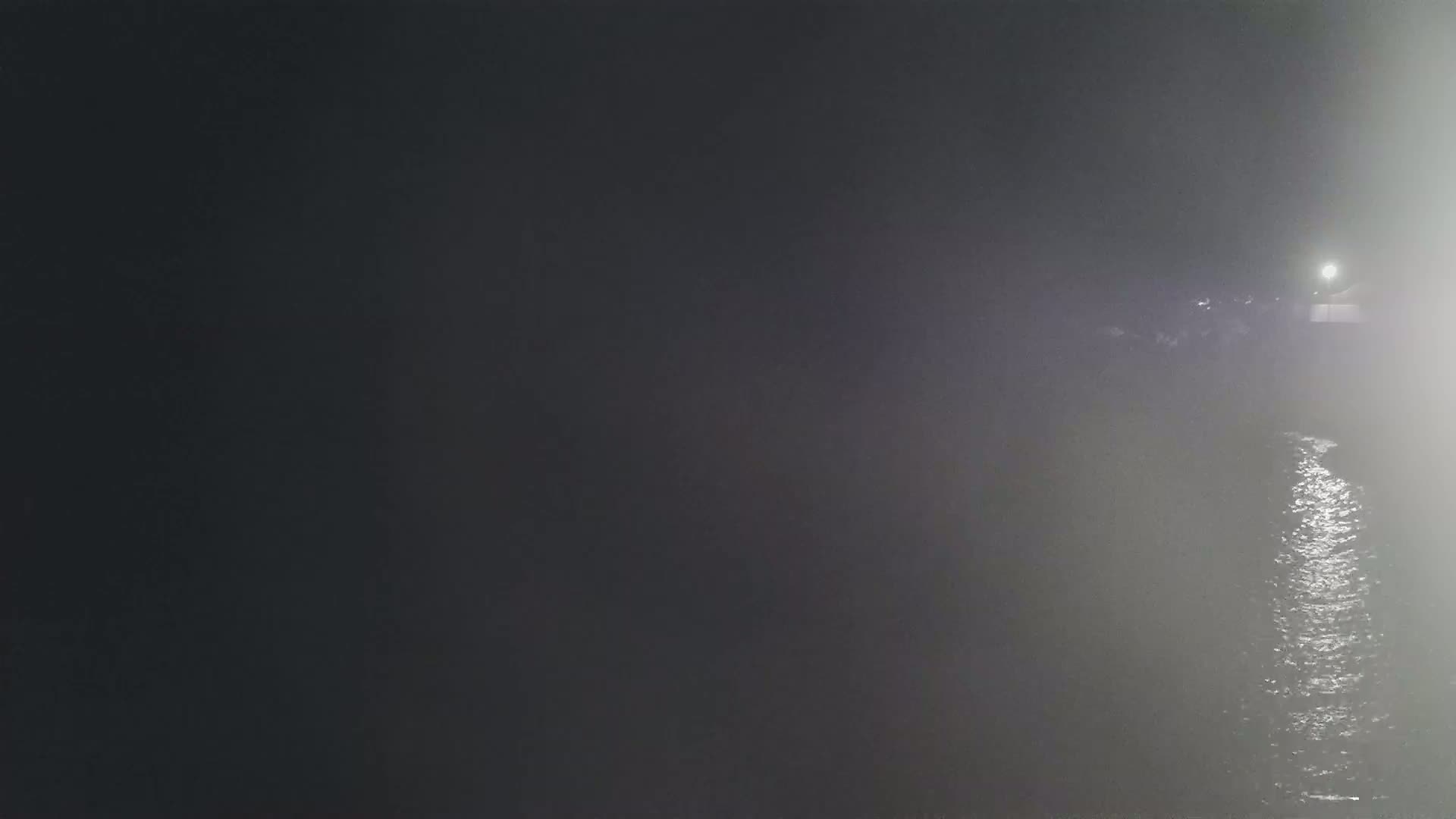 A dimly lit body of water is visible at night, partially obscured by fog or mist.