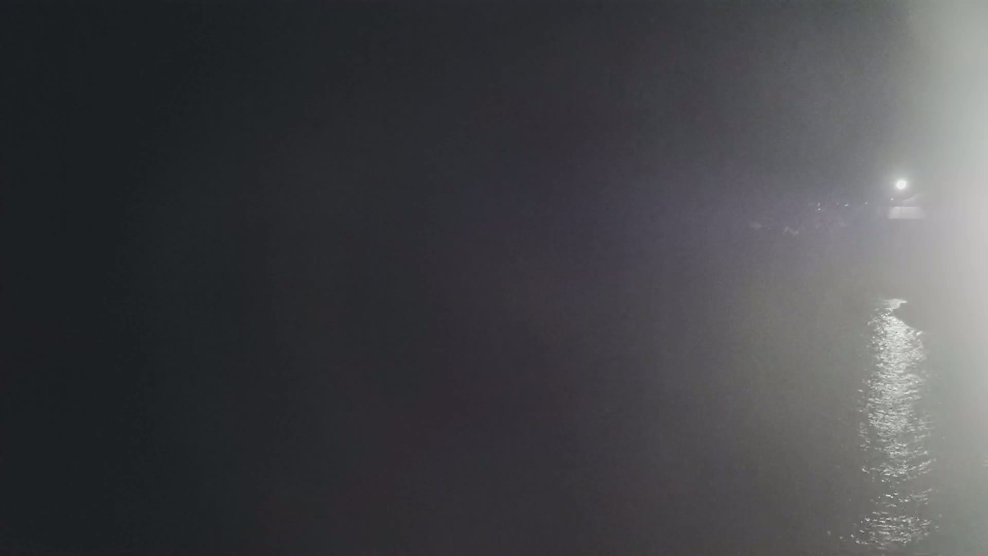 A dimly lit body of water is visible at night, with fog or mist obscuring much of the scene.