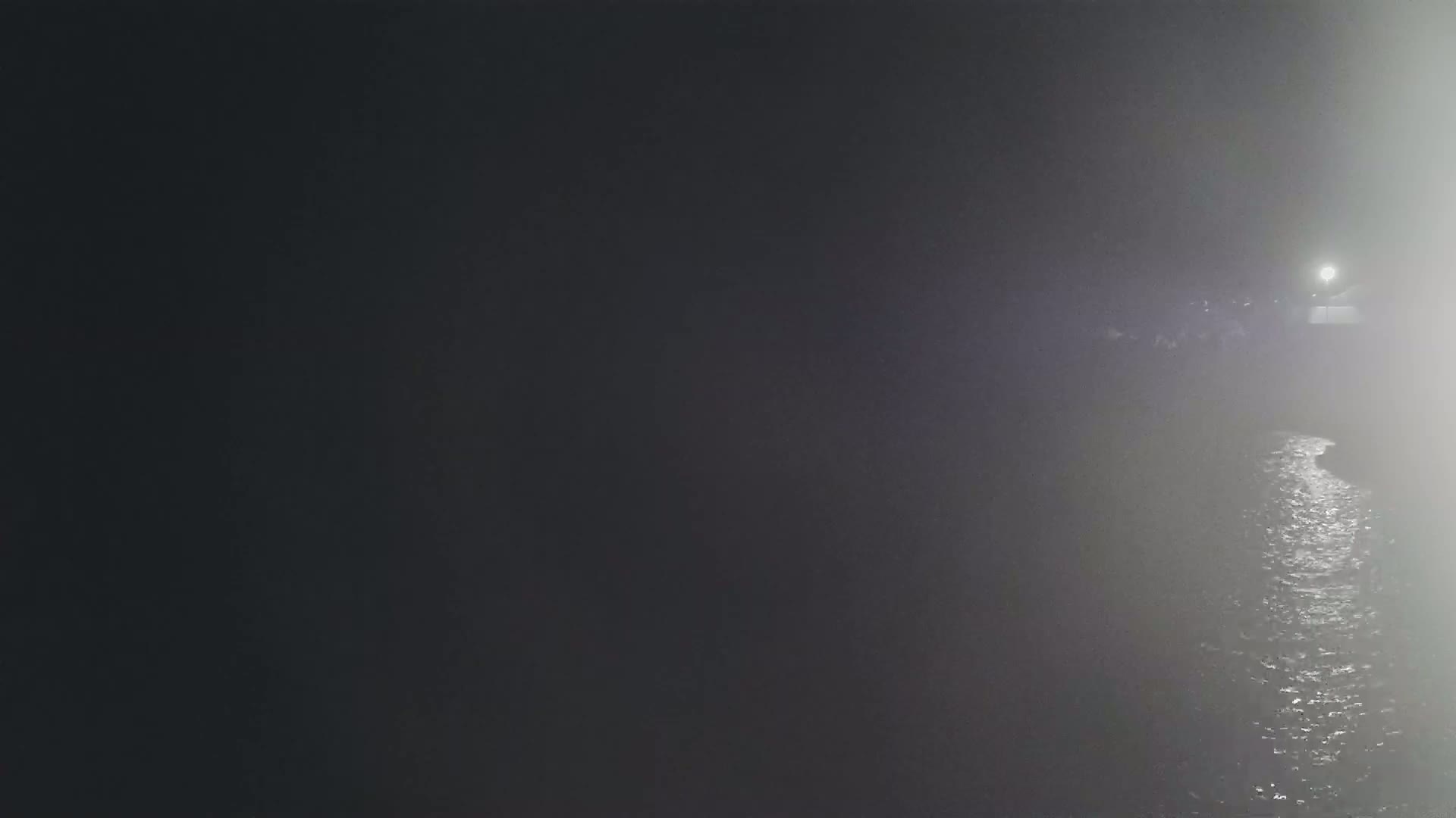 A dimly lit body of water is visible in the foggy night.