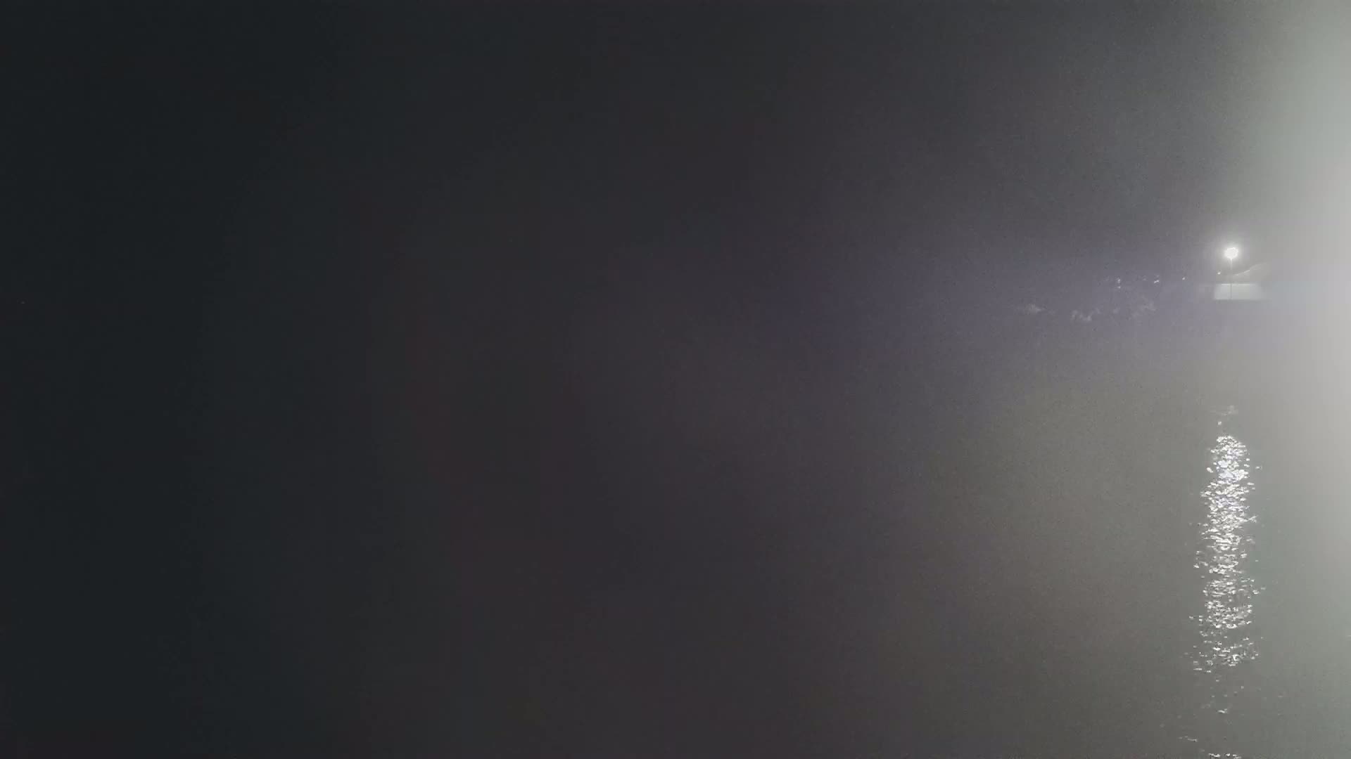 A dimly lit body of water is visible at night, shrouded in fog or mist.