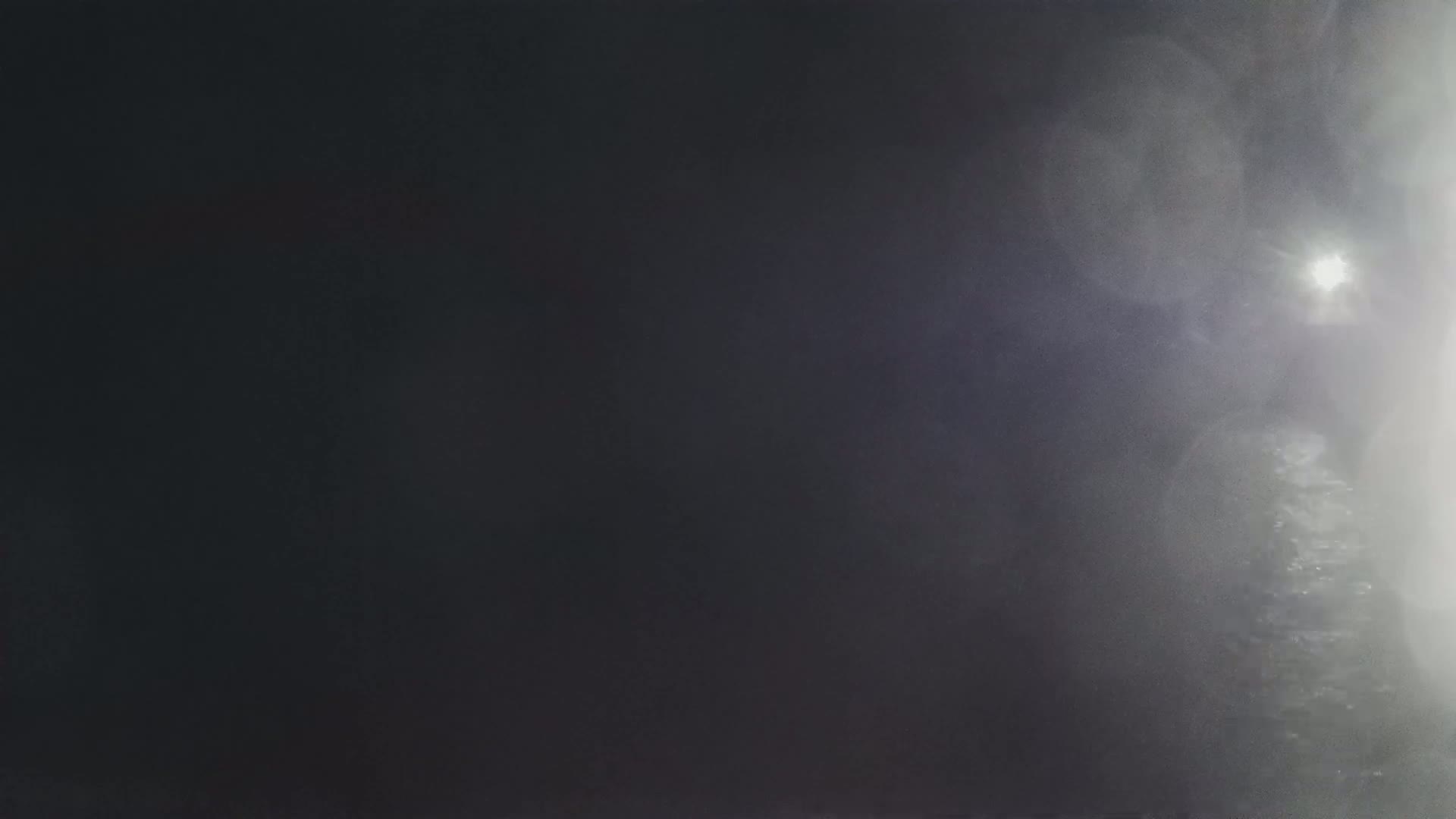 A bright light shines through a hazy, dark atmosphere.