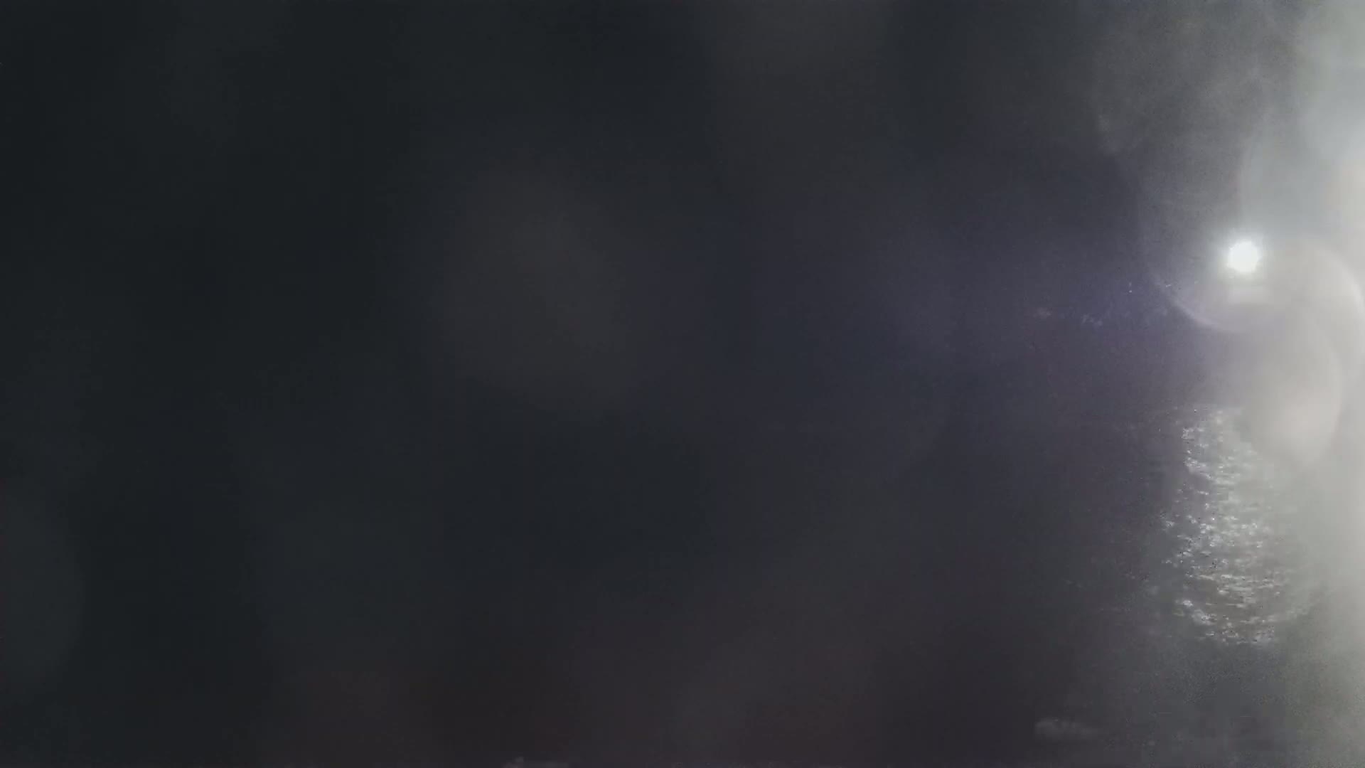 A blurry, dark image shows a bright light source through a misty or foggy atmosphere.