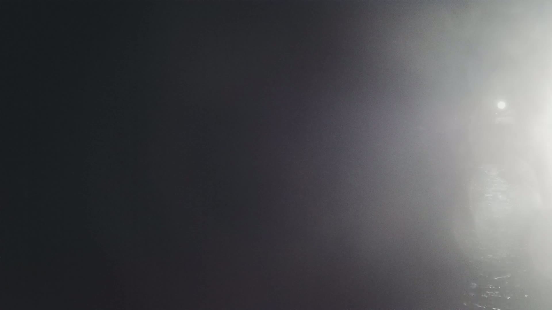A dimly lit, foggy scene shows a bright light in the distance.