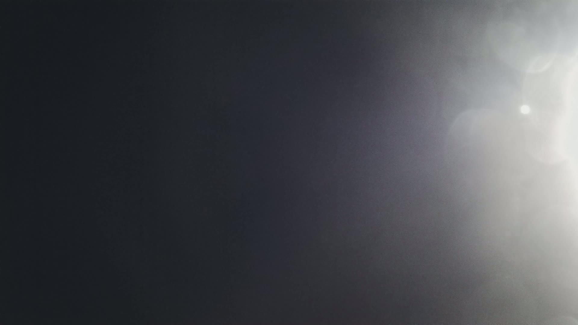 A dark gray surface is brightly lit from the upper right corner, creating a lens flare effect.