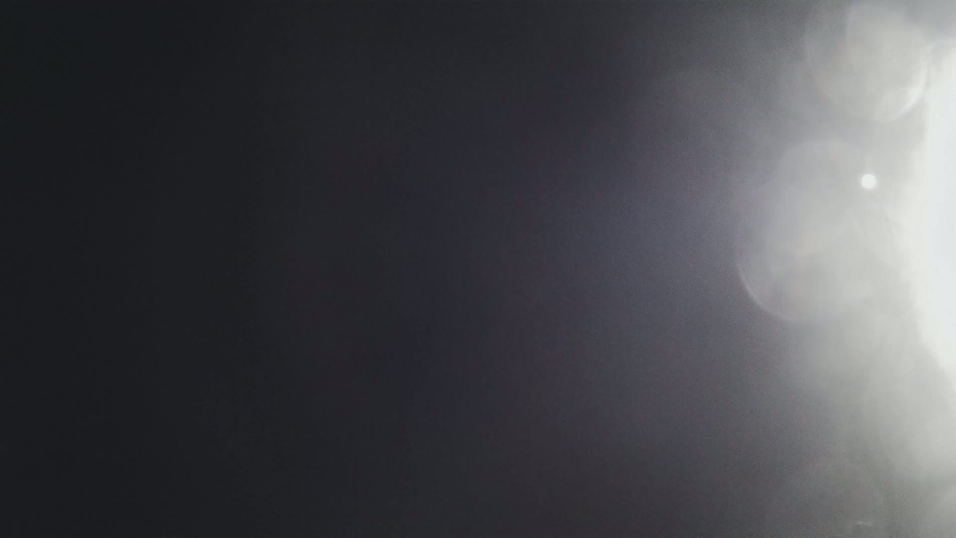 A bright light source, possibly the sun, shines through a hazy or foggy atmosphere, creating lens flares and a gradient from dark to light.