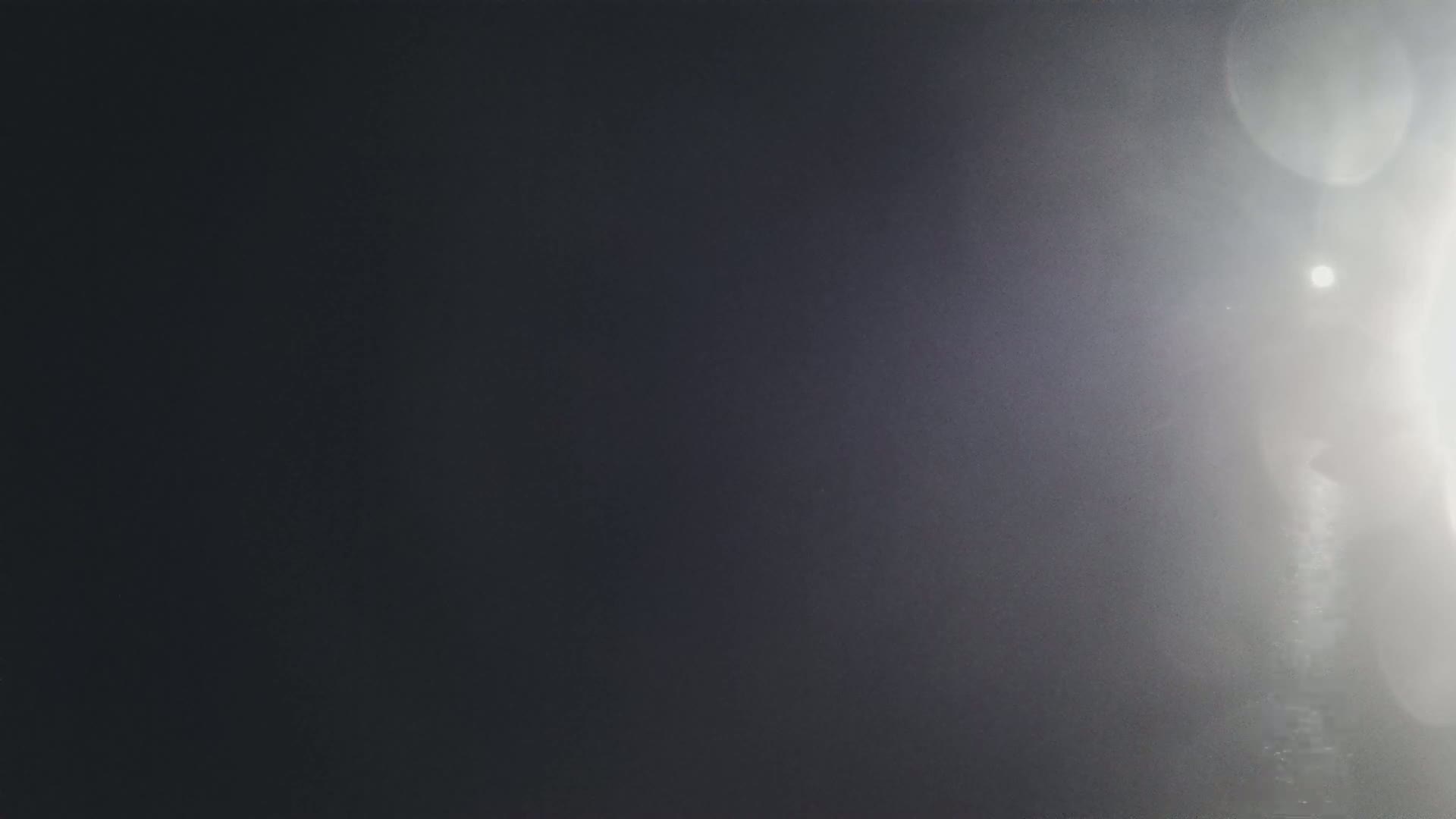 A bright, hazy sun shines through a mostly dark and blurry background.