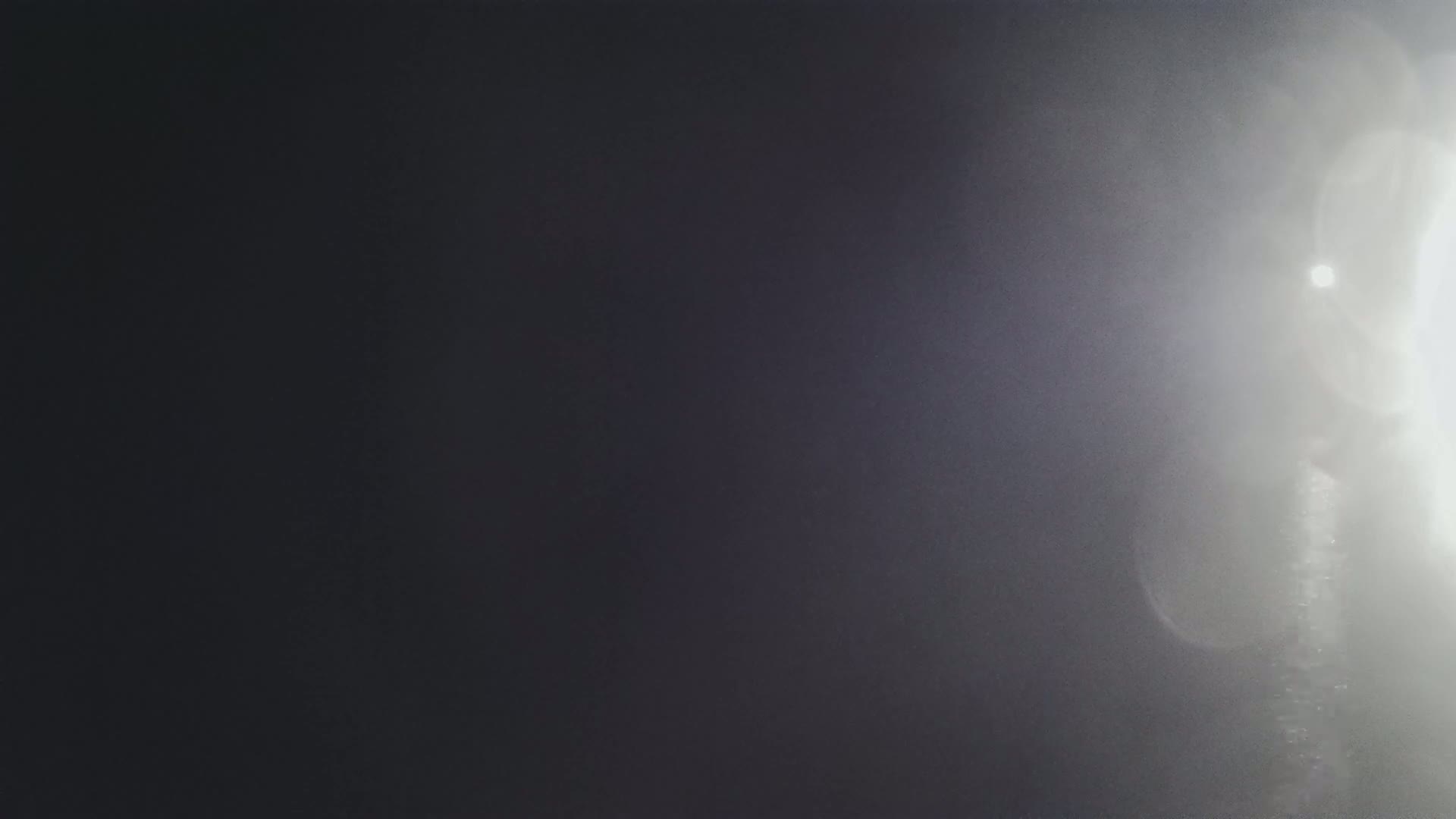A dark, blurry image shows a bright light source on the right side, creating lens flares and a hazy effect.