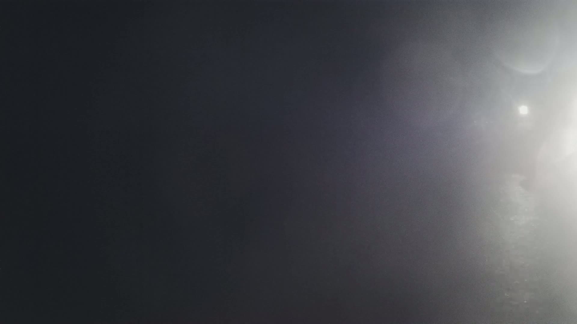 A dark gray surface is brightly lit on the right side, creating lens flare and a hazy effect.