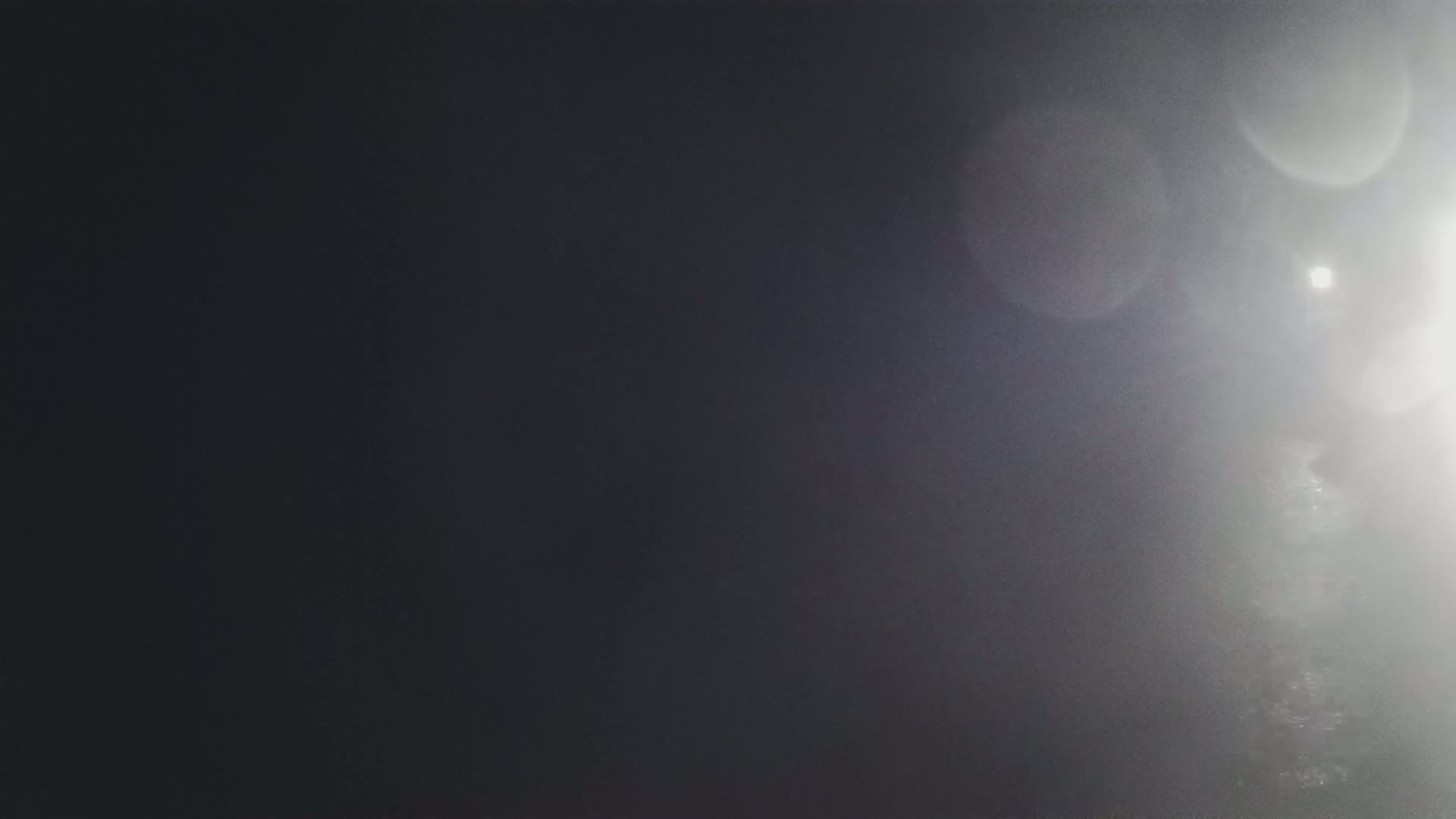 A bright light shines through a hazy atmosphere, creating lens flares.