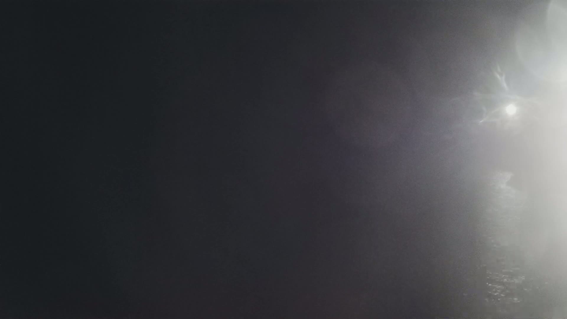 A blurry image shows a bright light in a dark, foggy environment.
