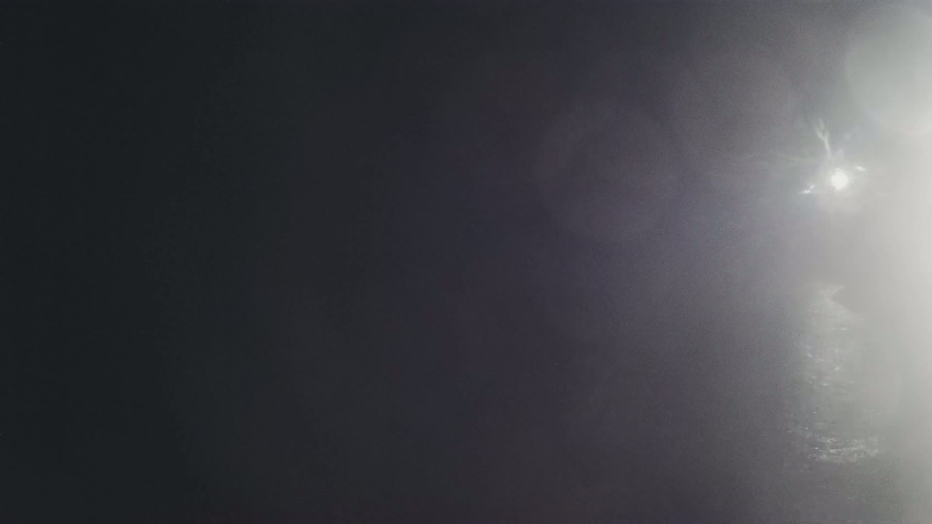 A bright light shines through a dense fog at night.