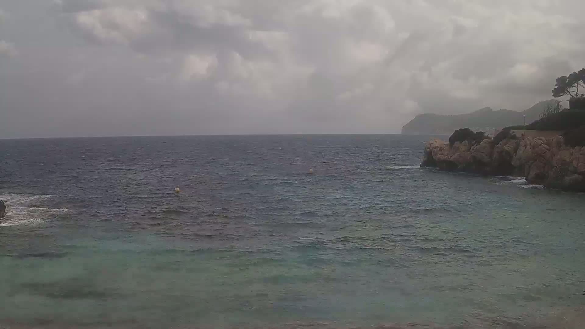 A rocky coastline meets a choppy sea under an overcast sky.