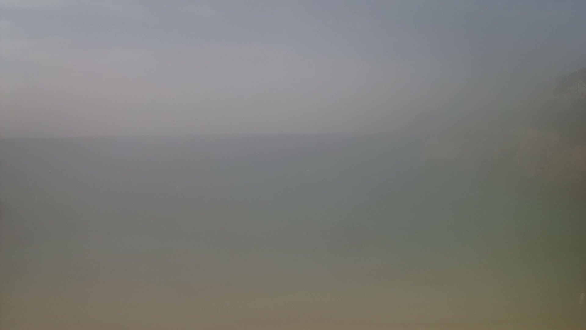 A hazy view of a body of water, possibly the ocean, is visible under a muted sky.