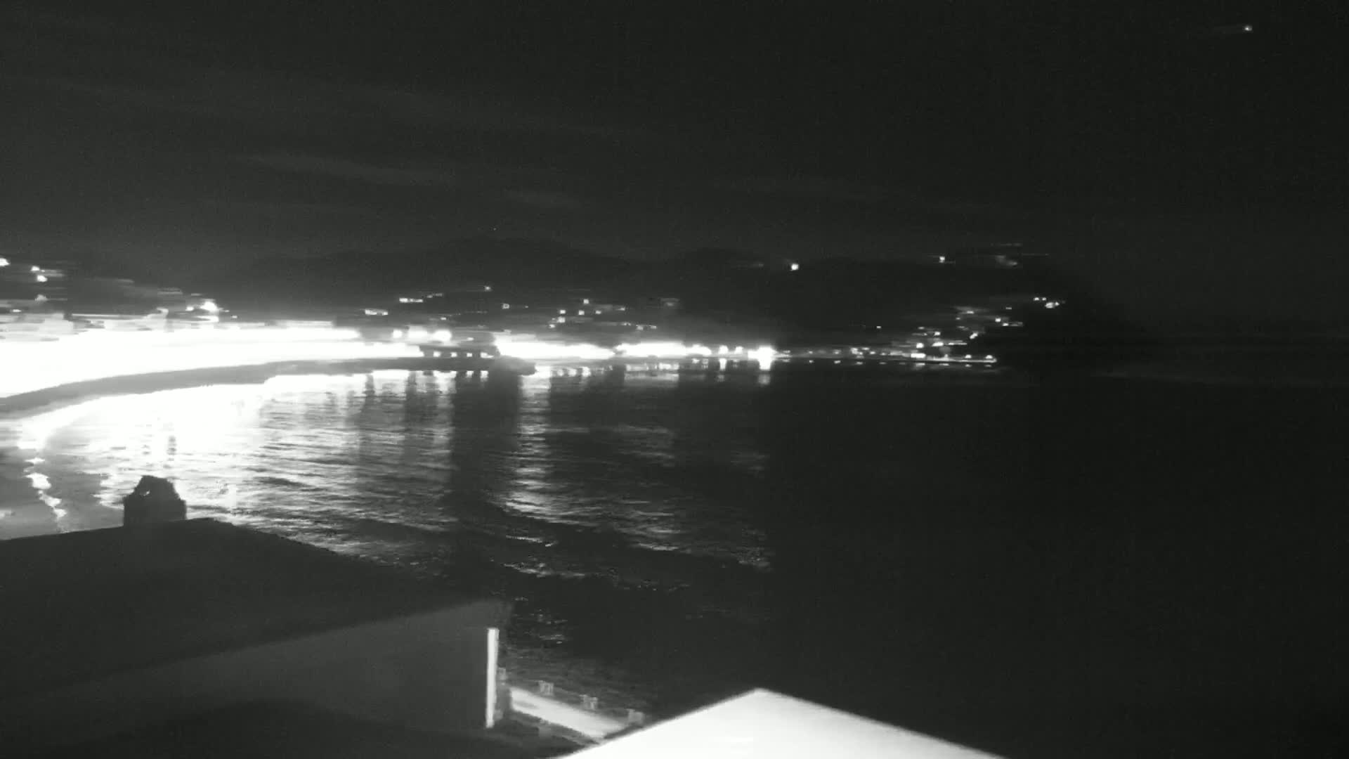 A nighttime view of a town's lights reflected on a calm body of water.