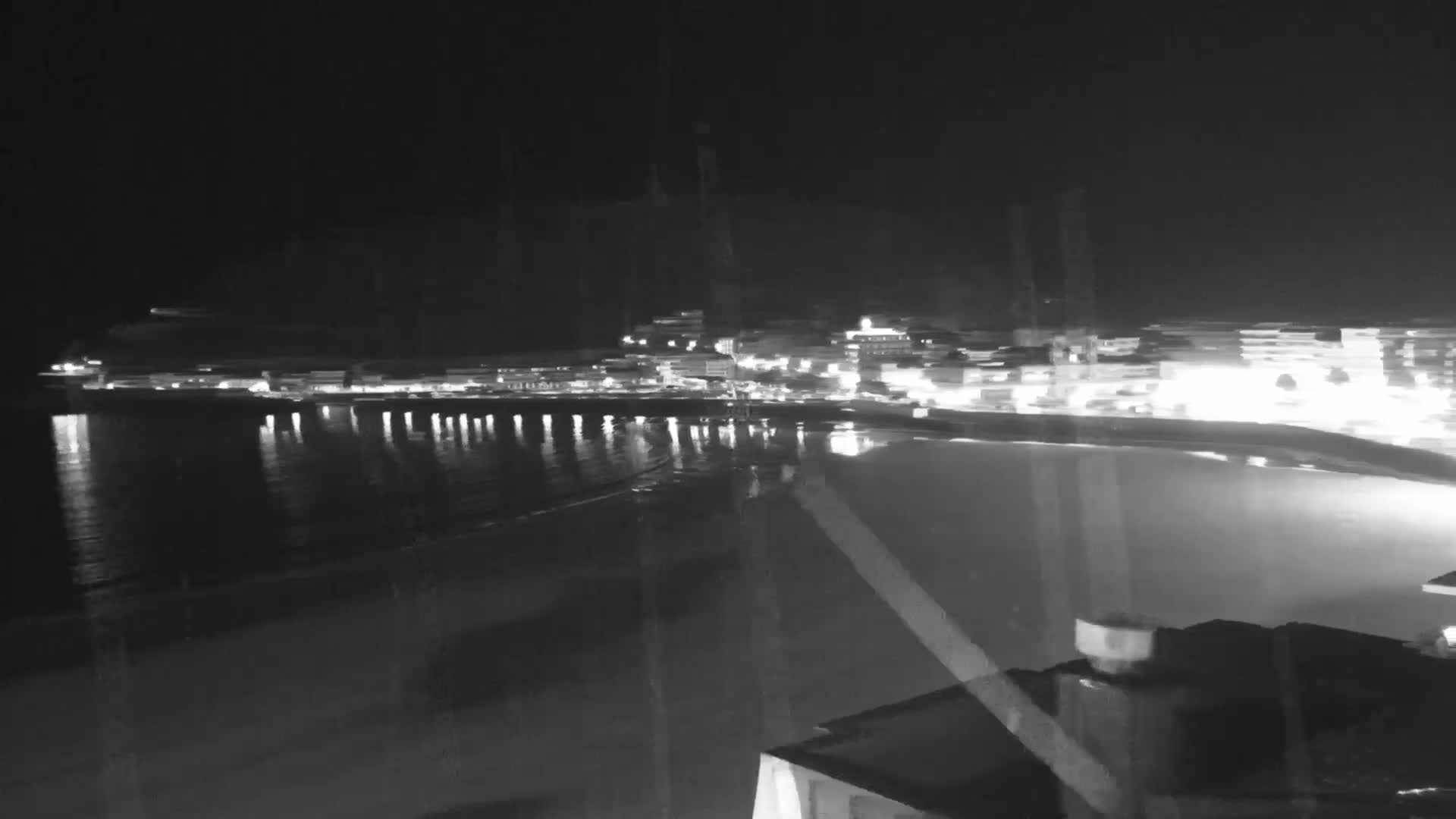 A nighttime view of a brightly lit coastal town across a calm, dark body of water.