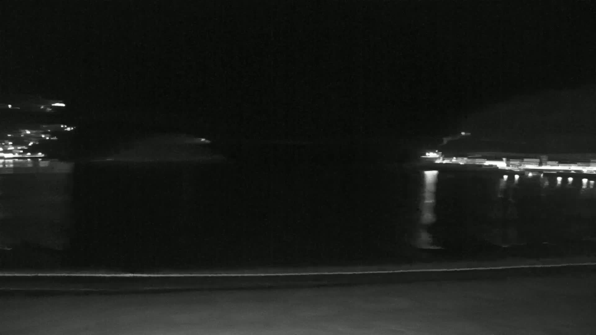 A nighttime view of a dark body of water reflecting the lights of buildings on opposite shores.
