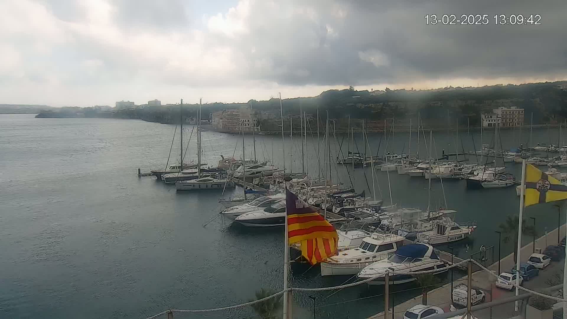 A marina filled with numerous boats and yachts is seen under an overcast sky.
