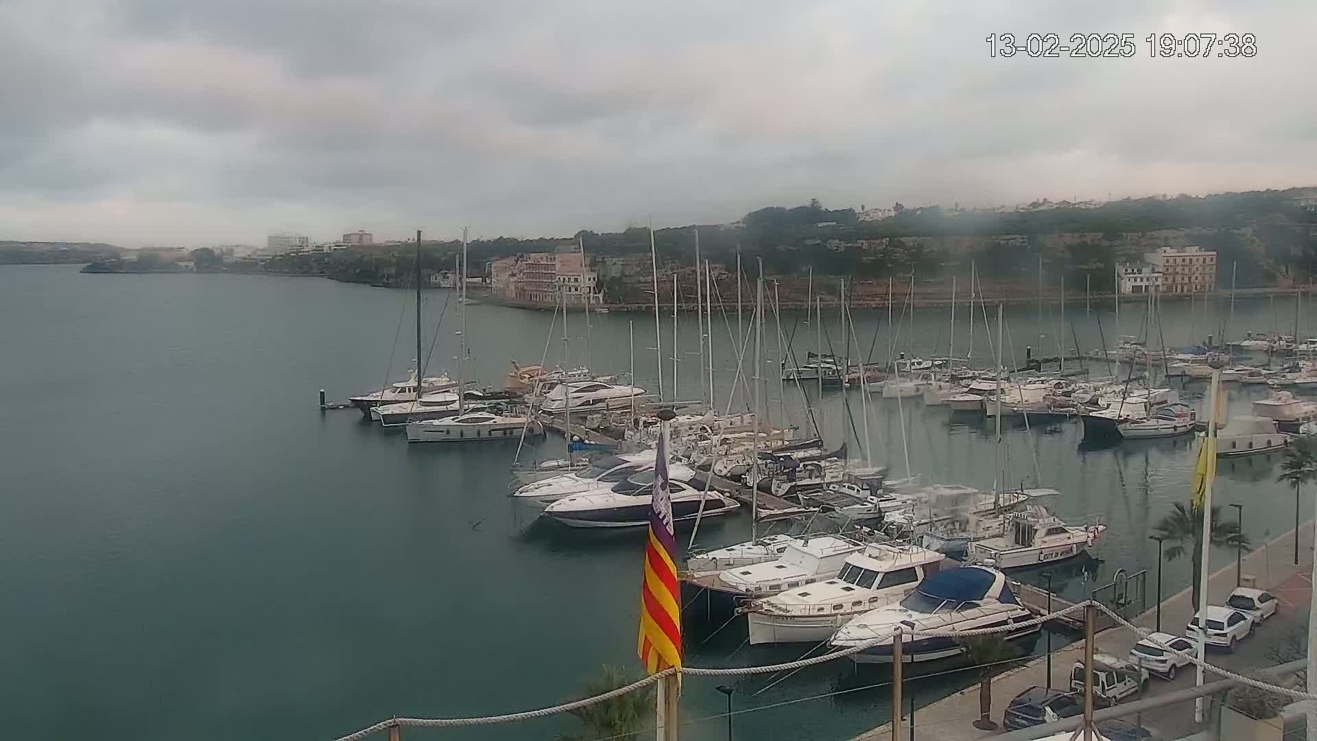 A harbor filled with many sailboats and motorboats on a cloudy day.