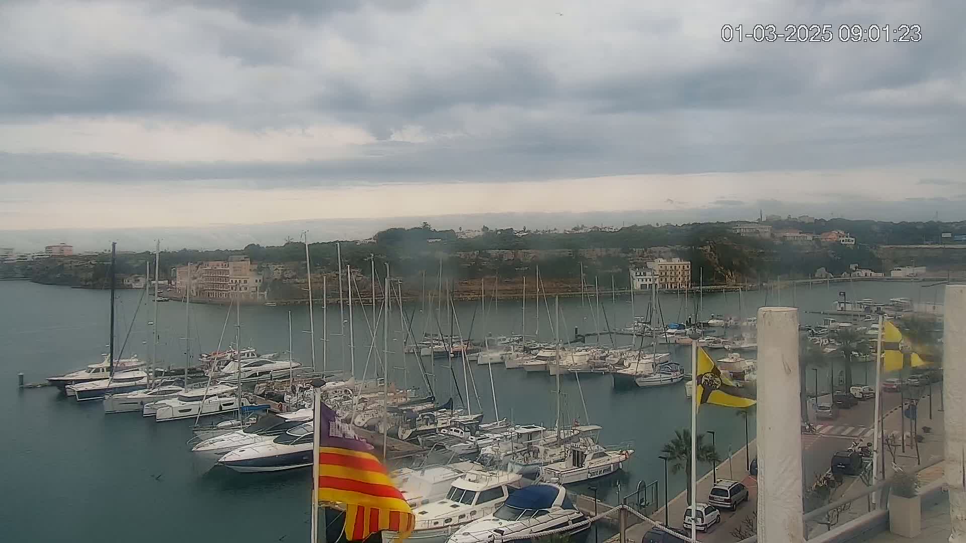 A harbor filled with numerous sailboats and motorboats under a cloudy sky.