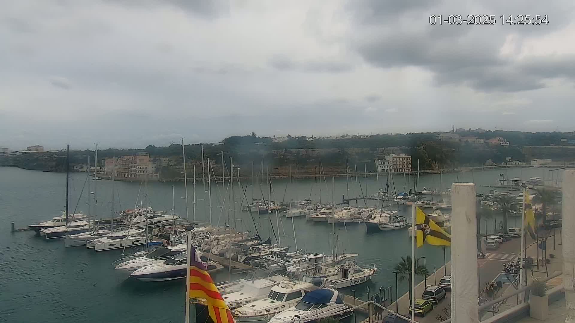 A harbor filled with numerous sailboats and motorboats under a cloudy sky.