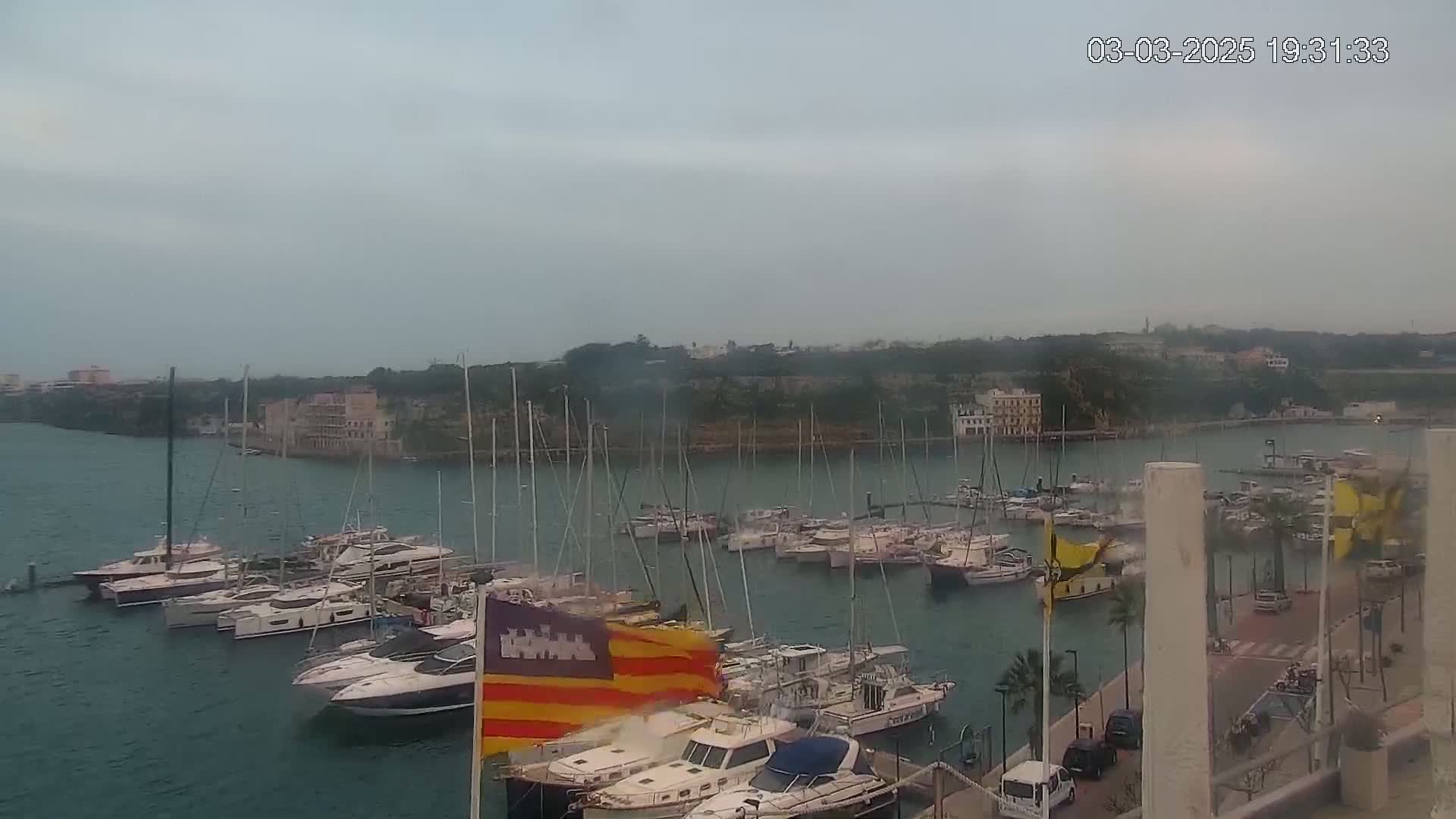 Numerous boats are docked in a harbor on an overcast day.