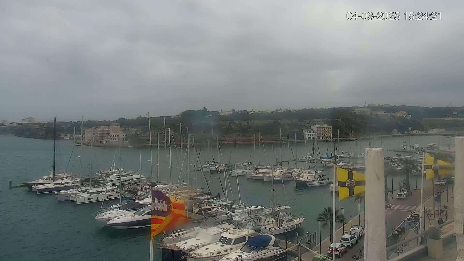 A harbor filled with numerous sailboats and motorboats under an overcast sky.