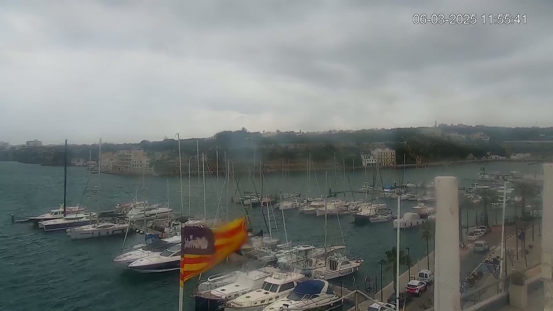 A marina filled with numerous boats and yachts is seen under an overcast sky.