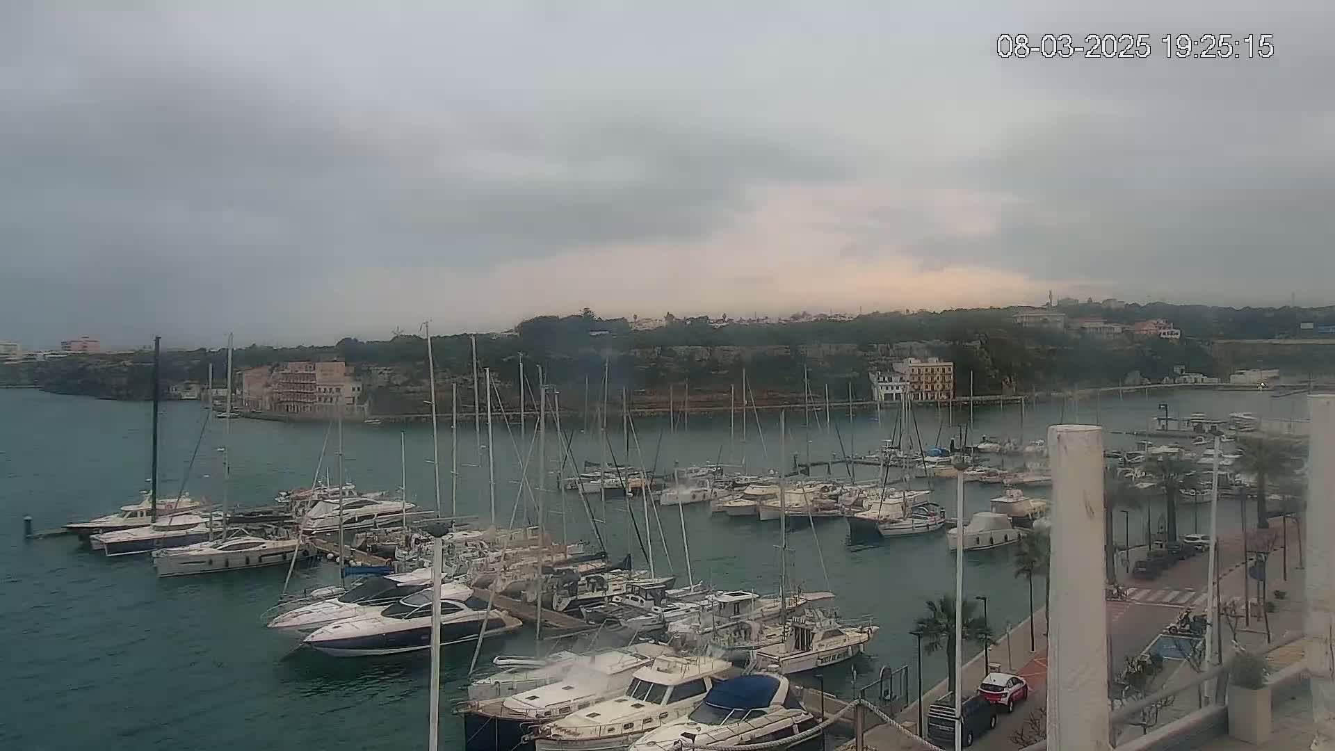 A marina filled with numerous boats and yachts under a cloudy sky.