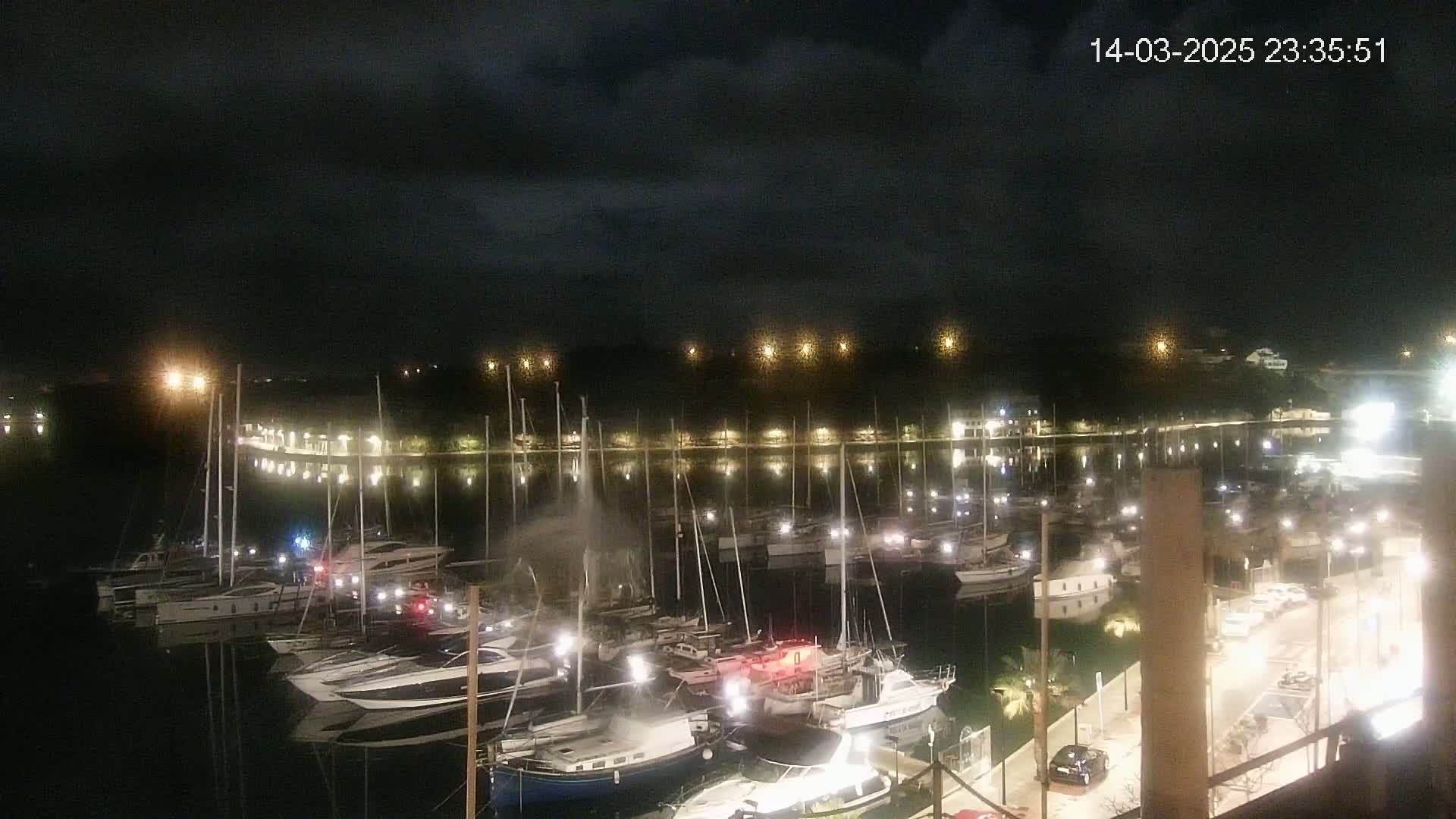 A nighttime view of a marina filled with boats under a dark, cloudy sky.