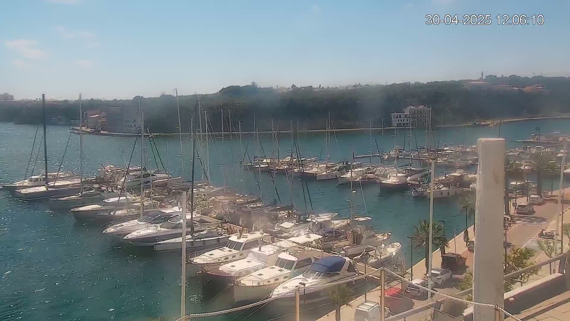 Numerous boats and yachts are docked in a marina on a sunny day.